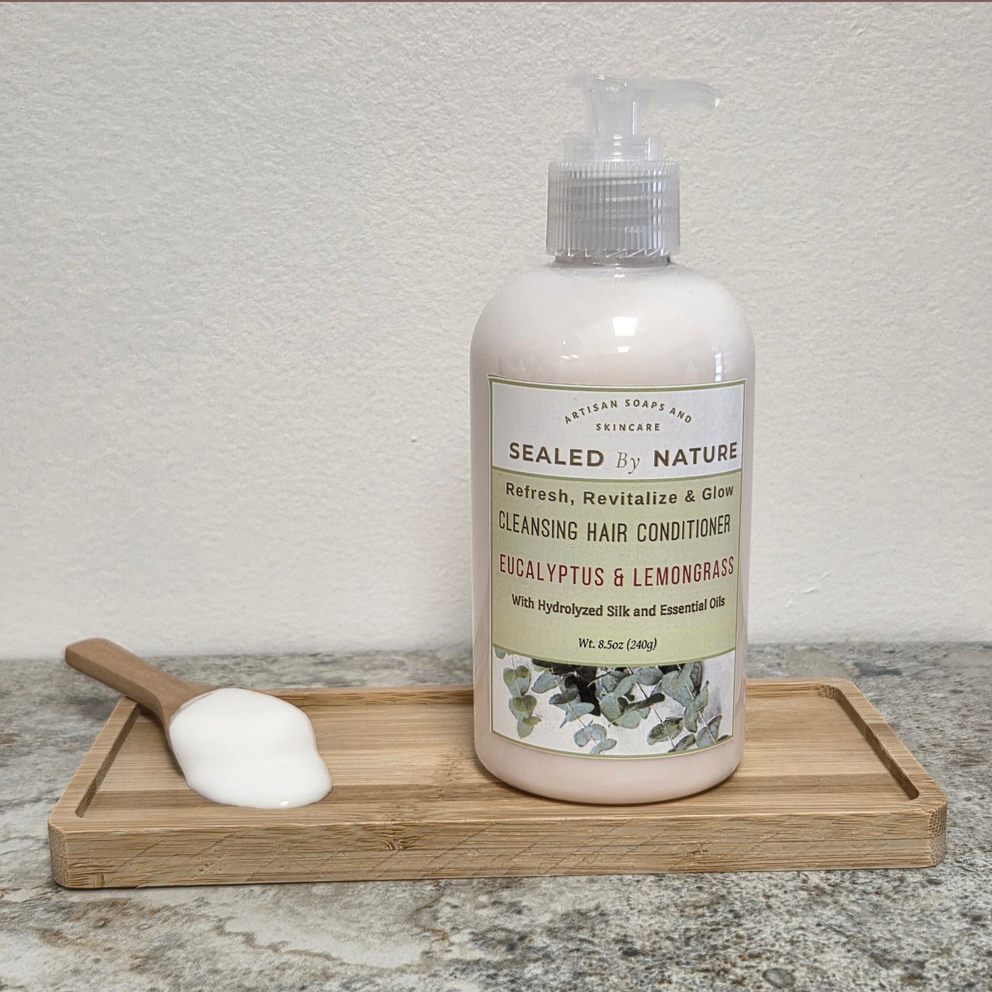 Bottle of cleansing hair conditioner with a wooden scoop on a tray against a neutral background