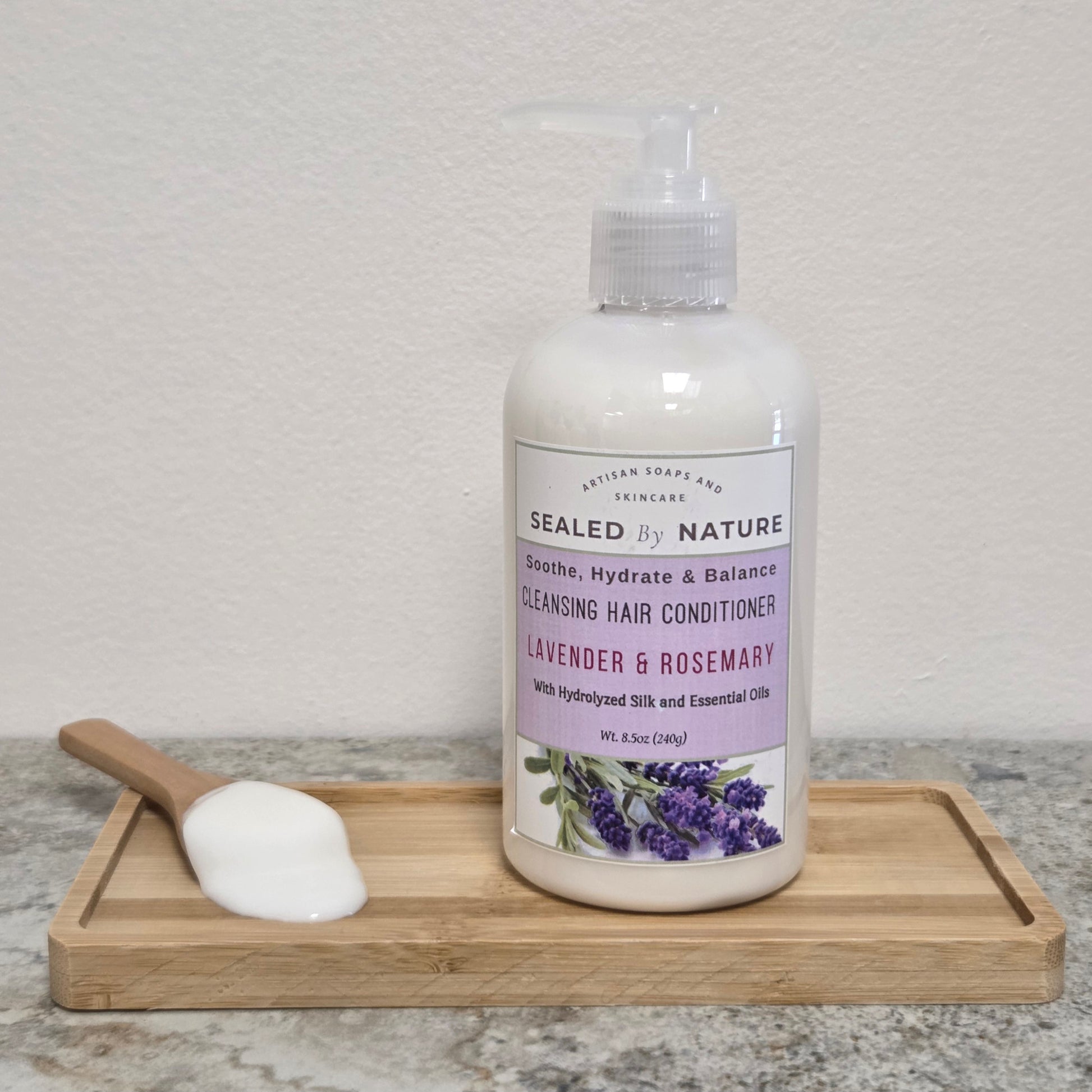 Bottle of Sealed by Nature cleansing hair conditioner with a wooden scoop on a tray against a neutral background