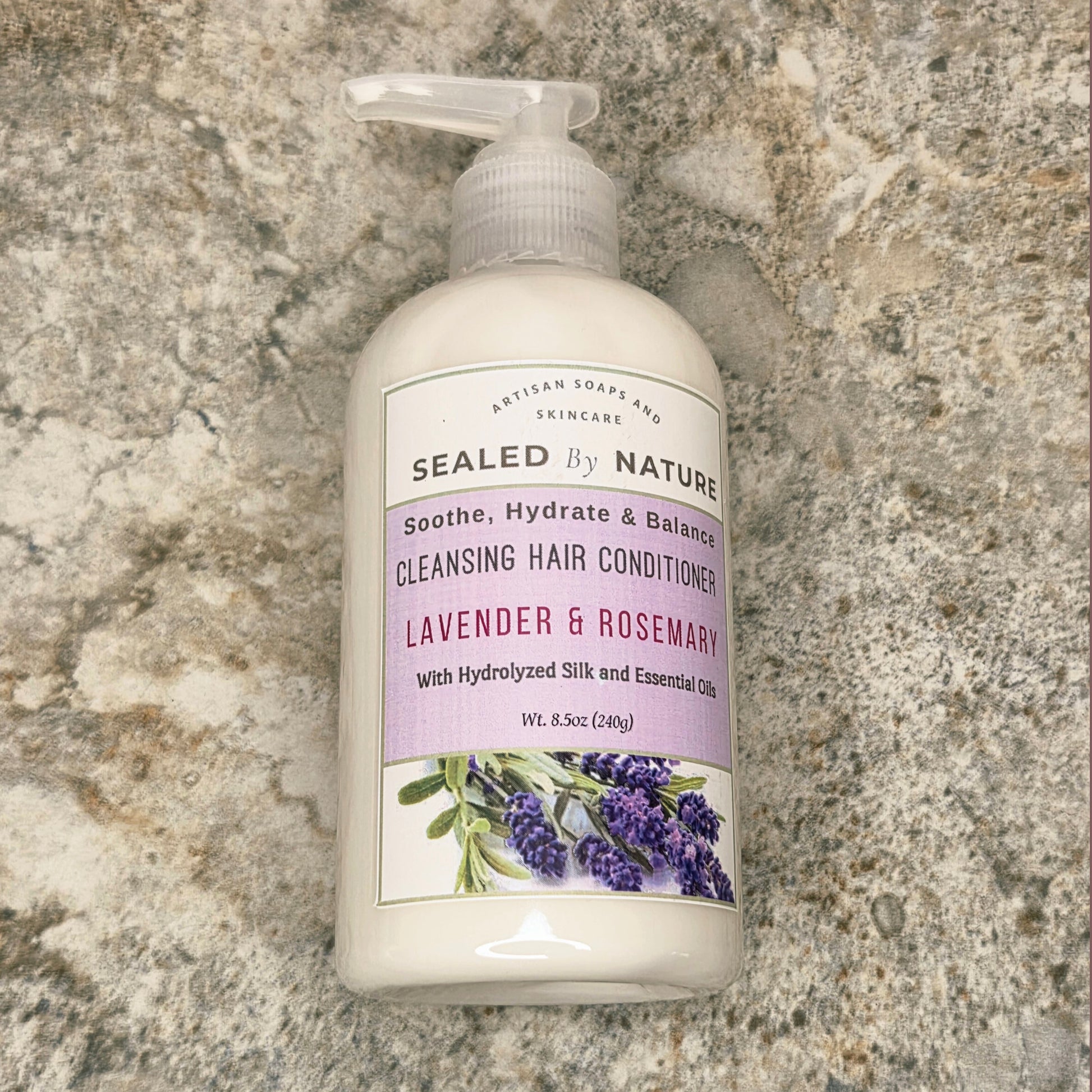 Bottle of Sealed by Nature cleansing hair conditioner on a stone surface