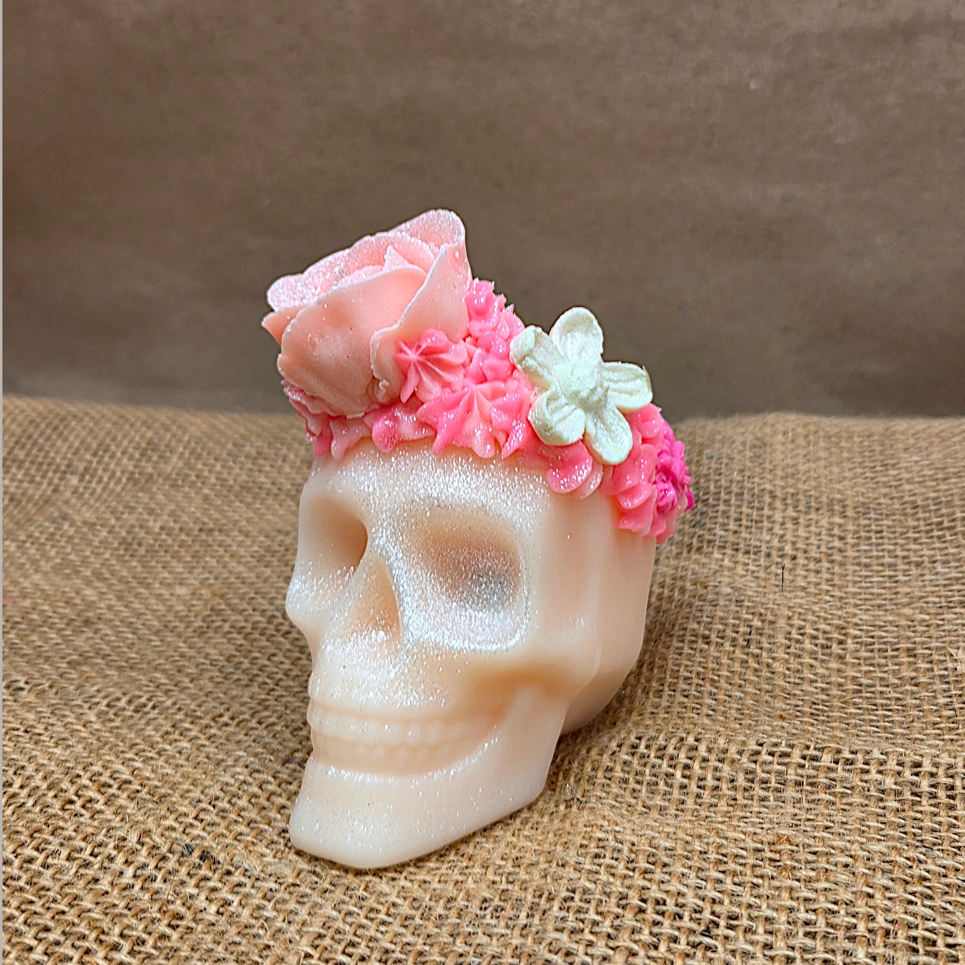 Skull-shaped soap with floral decorations on a burlap surface