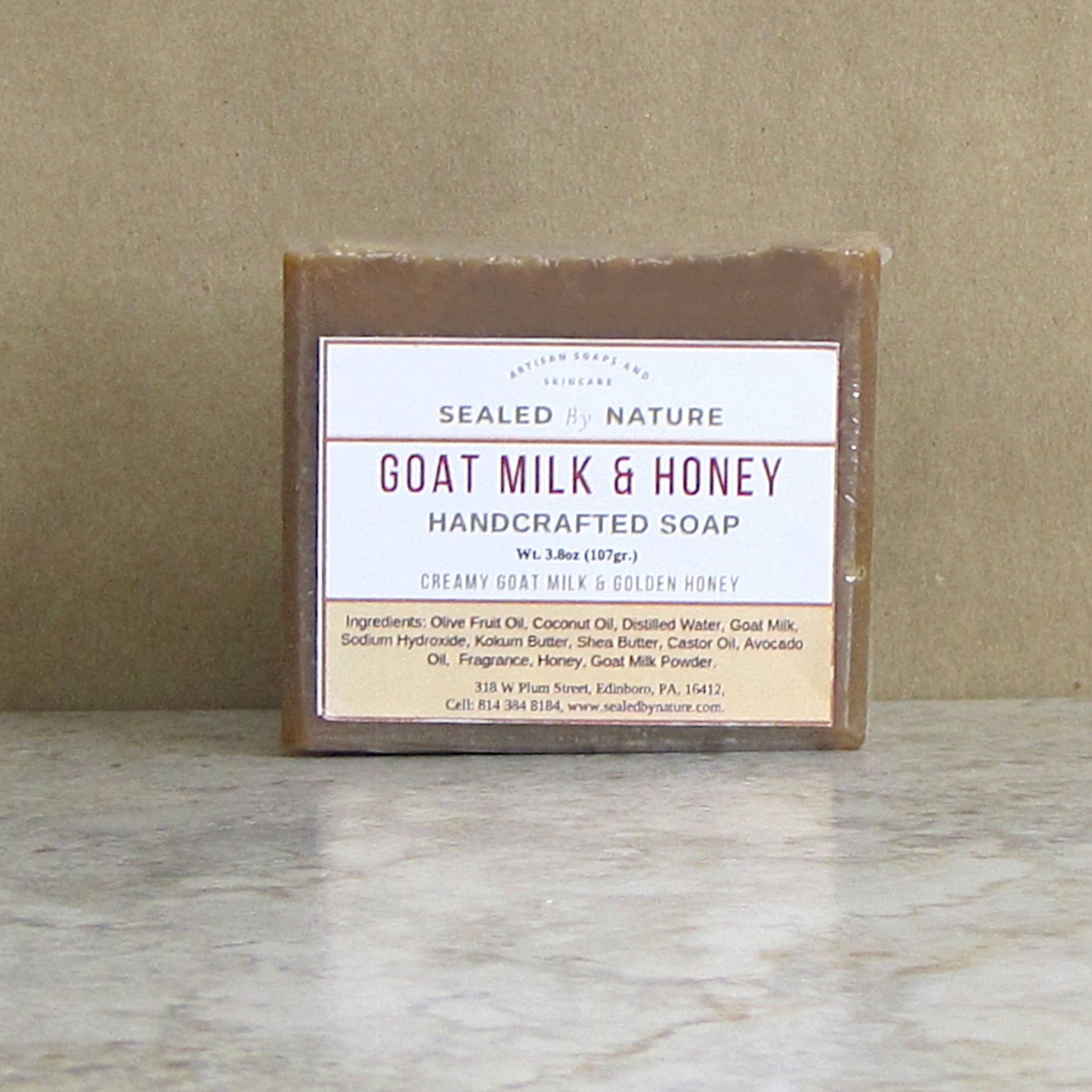 Bar of goat milk and honey handcrafted soap with a label on a marble surface.