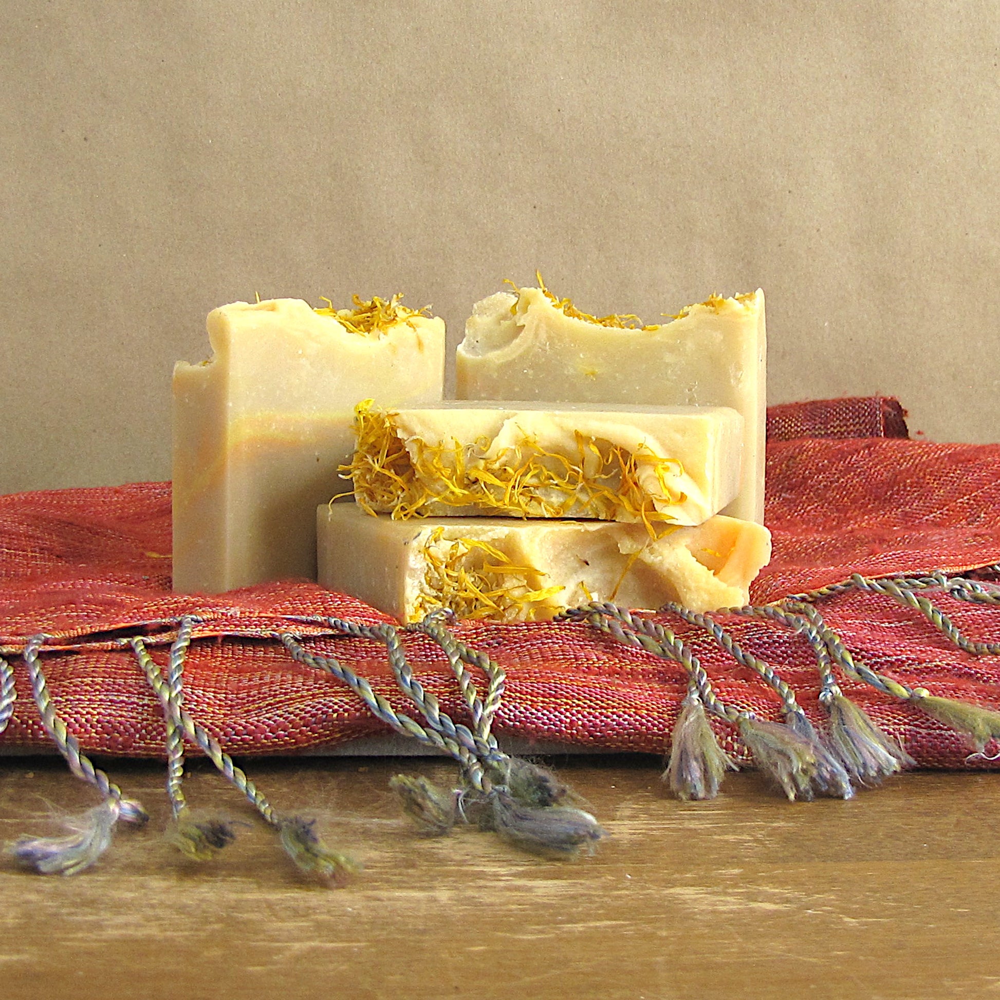 Three bars of soap with calendula petals on a red woven table cloth