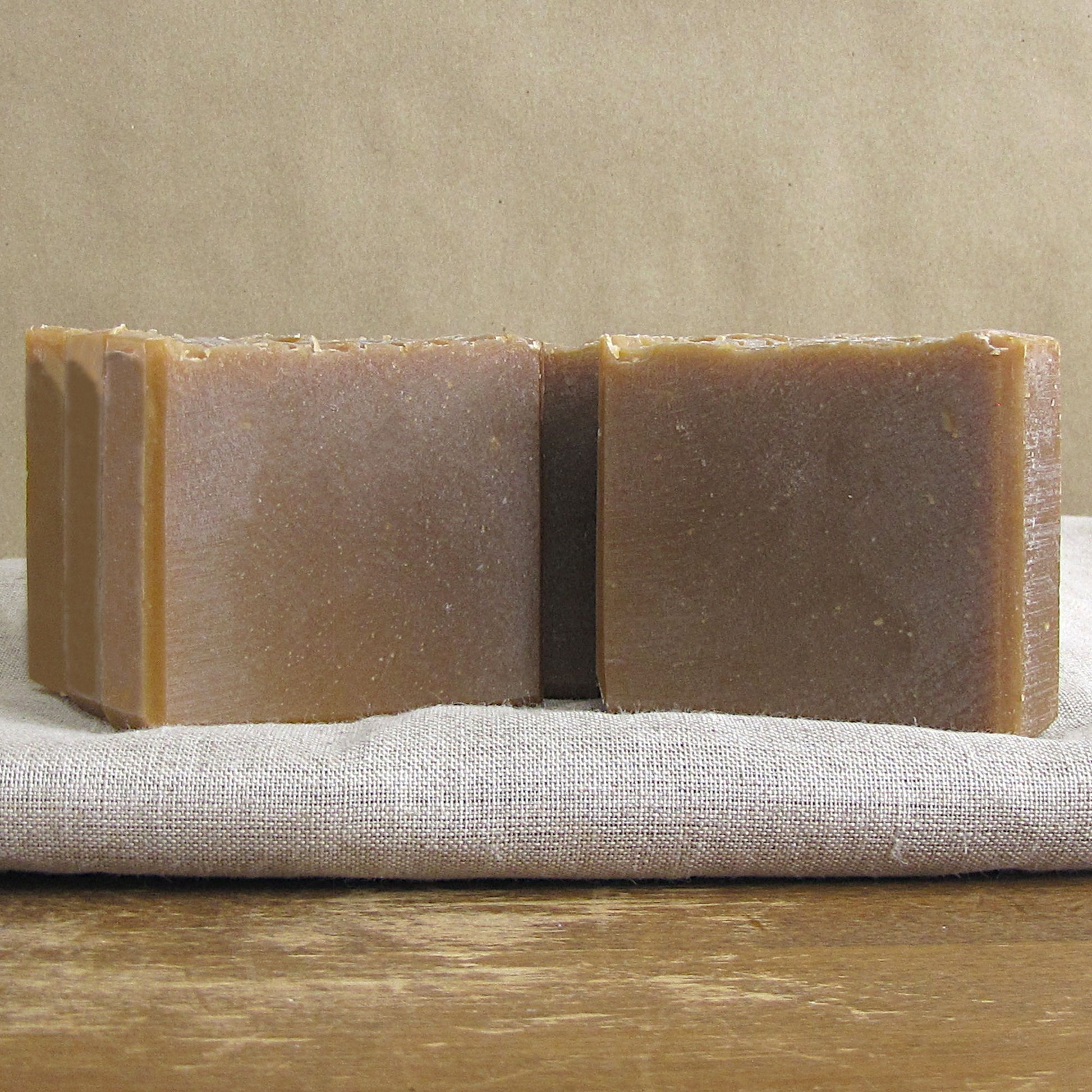 Rectangular bars of goat milk and honey soap on a textured surface with a neutral background