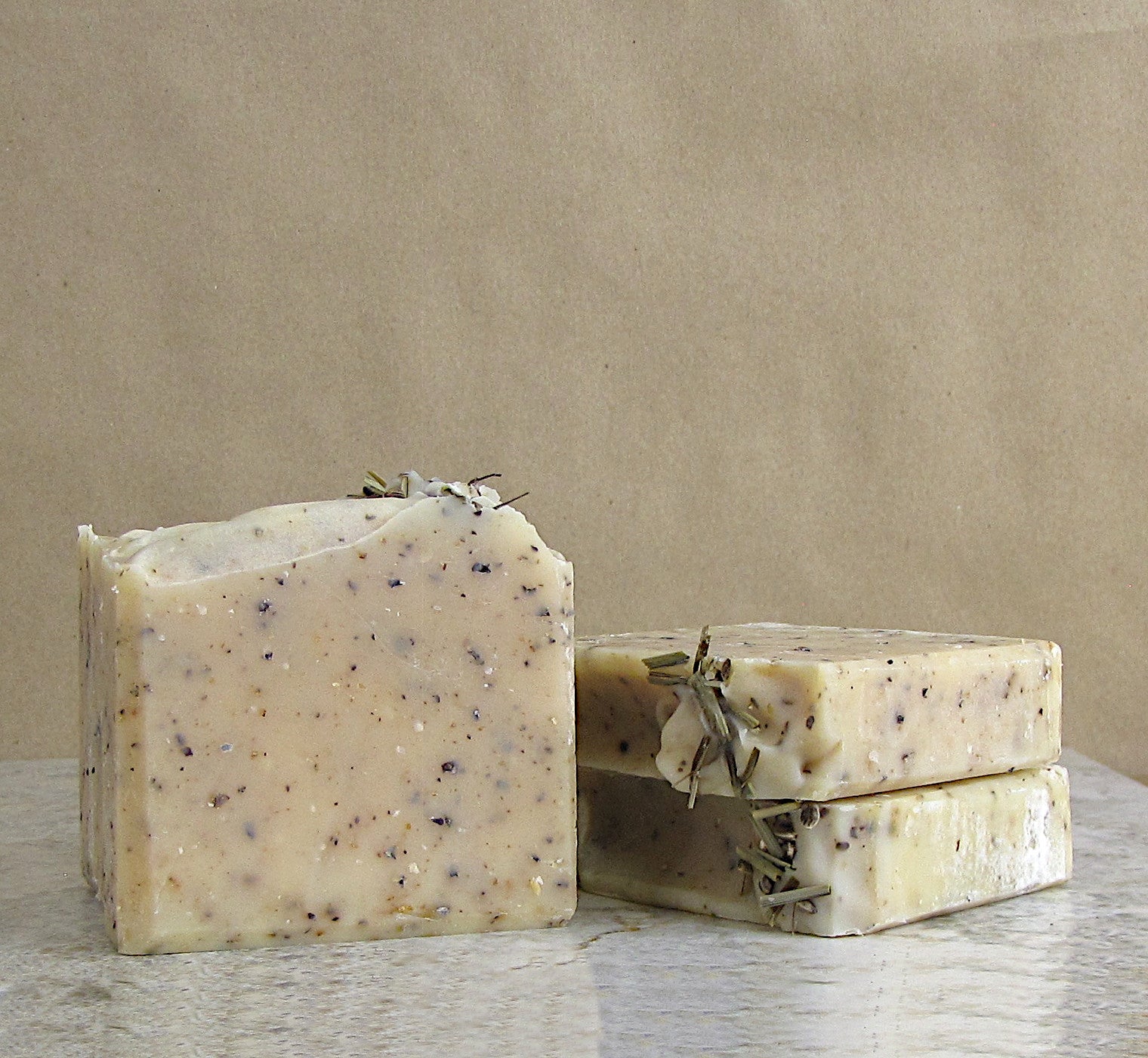 Three bars of soap with ground hemp inside on a wooden surface and brown background