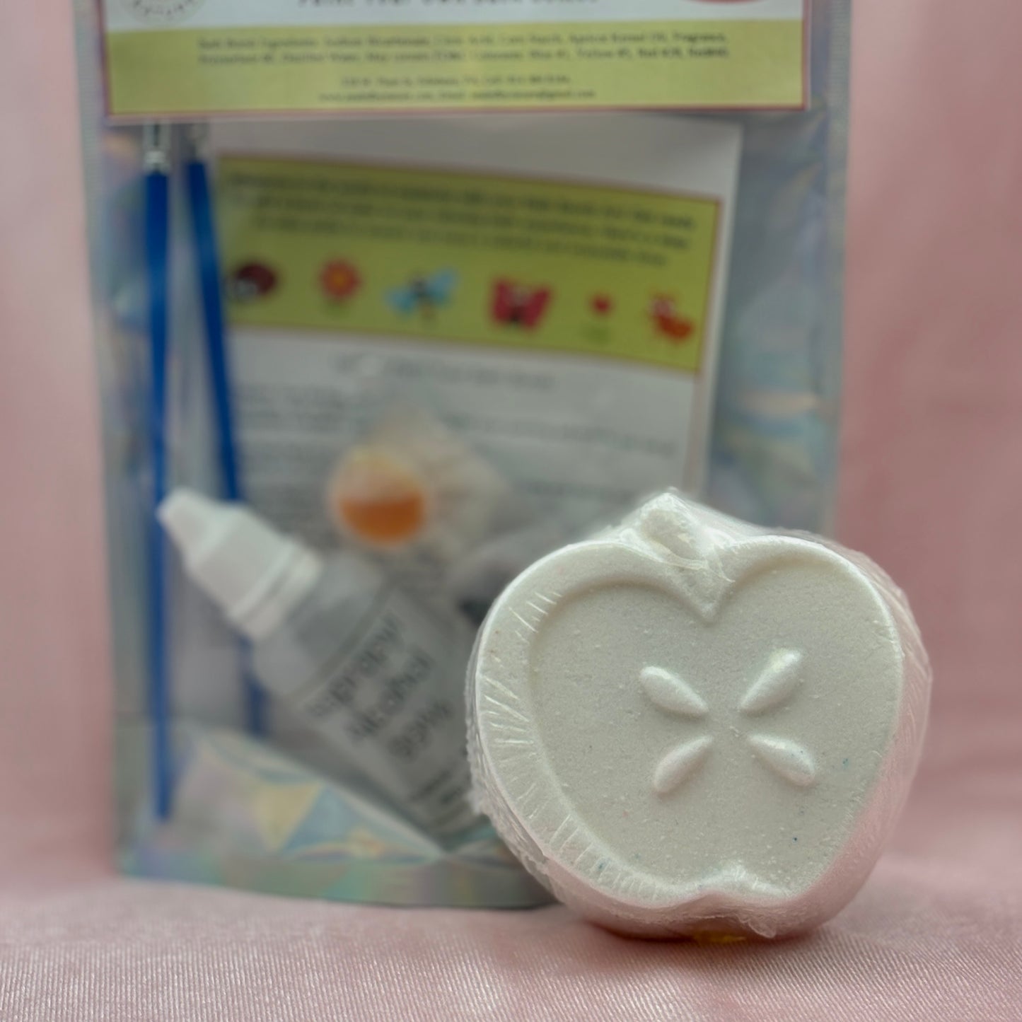 White sliced apple bath bomb for painting with the paint set in the background.