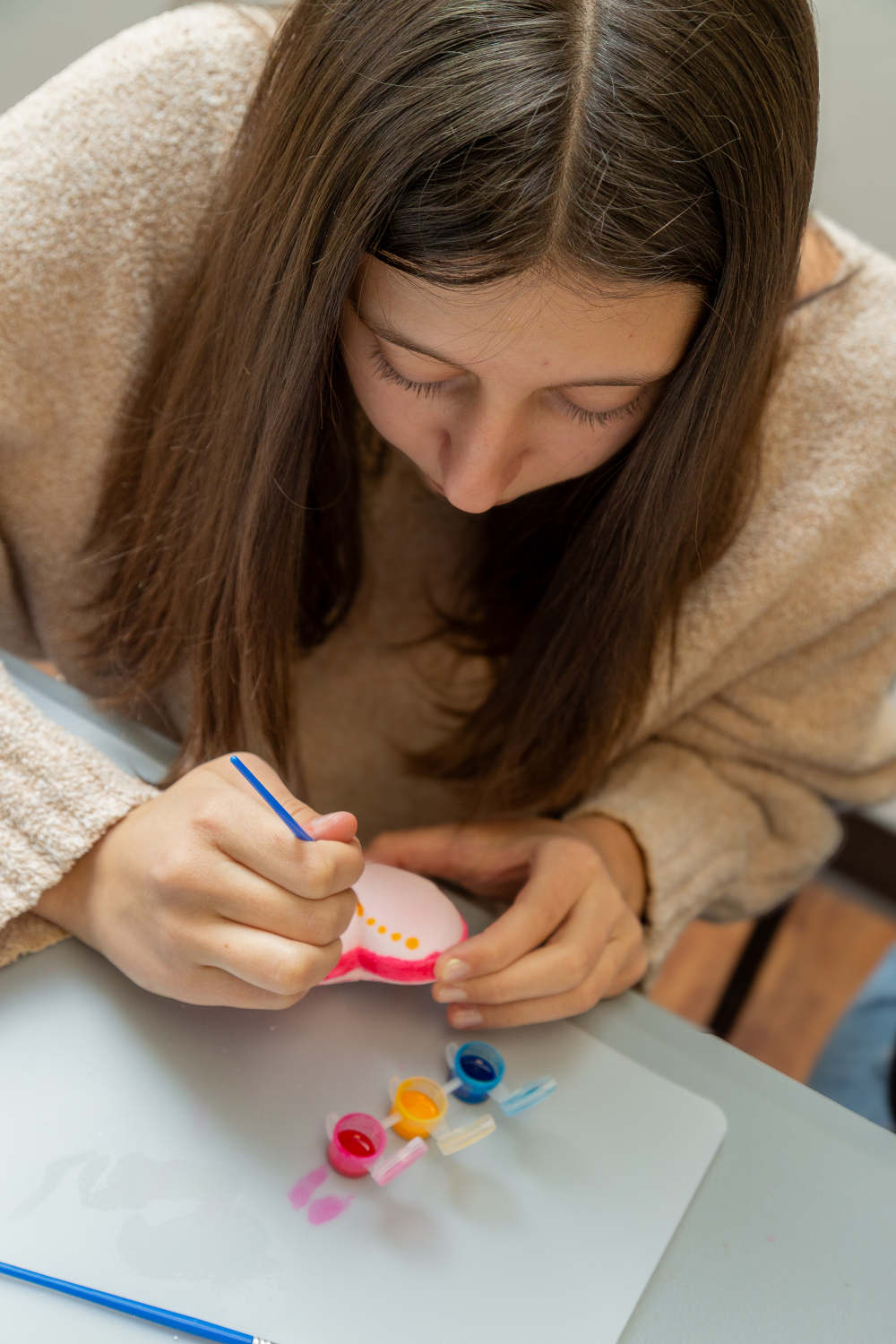 Person painting small heart bath bomb on a table.