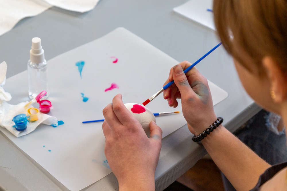 Person painting an egg bath bomb with skin safe colorant.