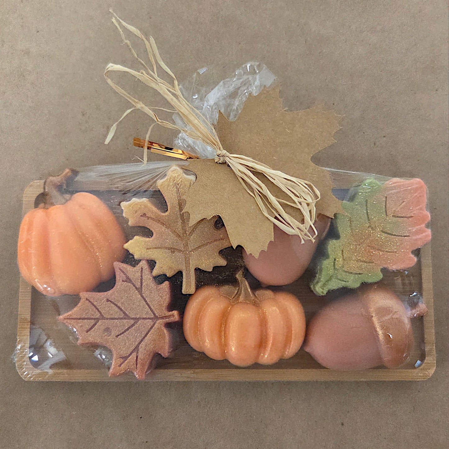 Set of small pumpkins and leaves in a clear packaging on a brown background