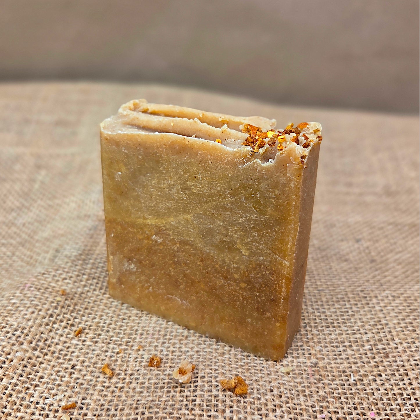 Bar of soap with visible herbs on a textured fabric background