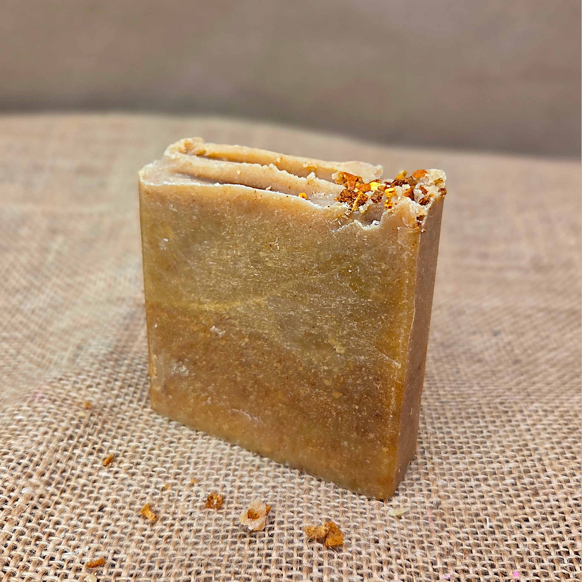 Bar of soap with visible herbs on a textured fabric background