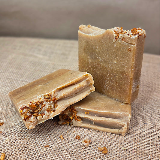 Three bars of brown soap with specks on a textured fabric background