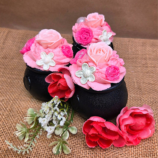 Decorative cauldrons with pink and red flowers on a brown fabric background