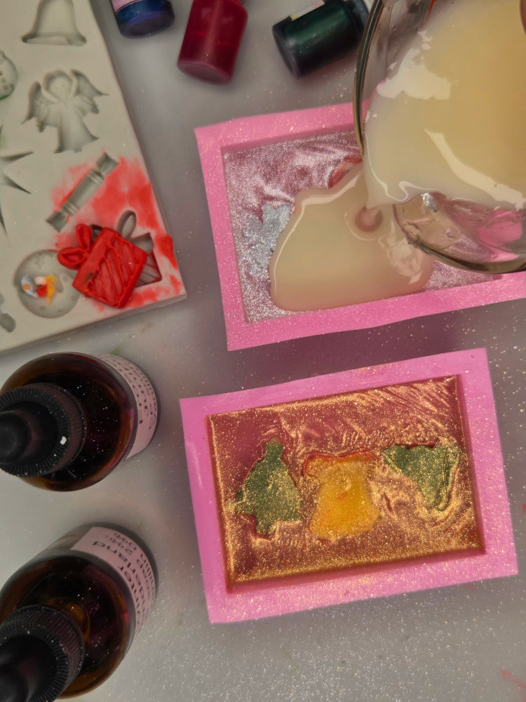 Artistic pouring of meltable soap into mold on a textured surface with bottles in the background.