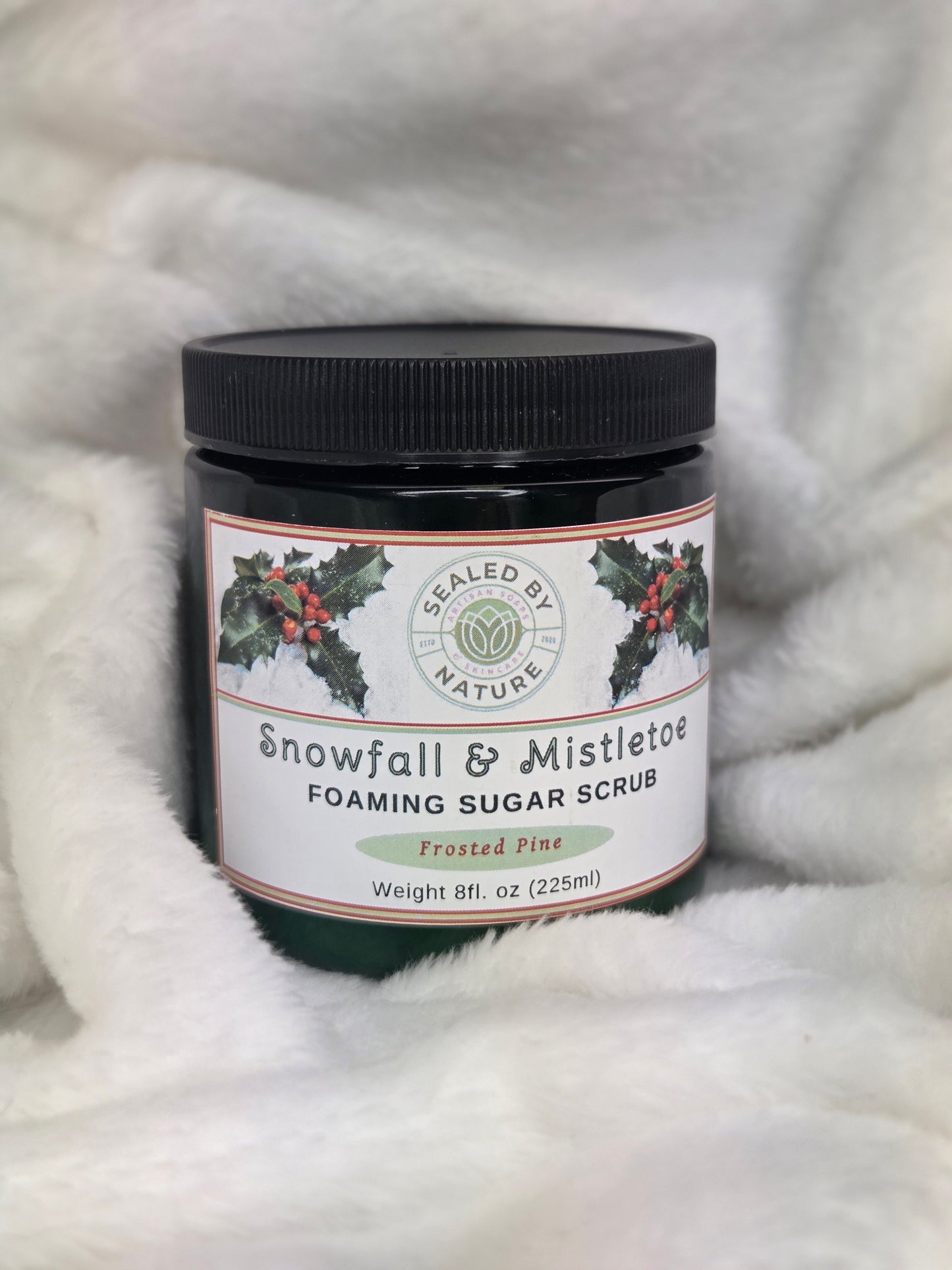 Jar of foaming sugar scrub with a label on a fluffy white surface