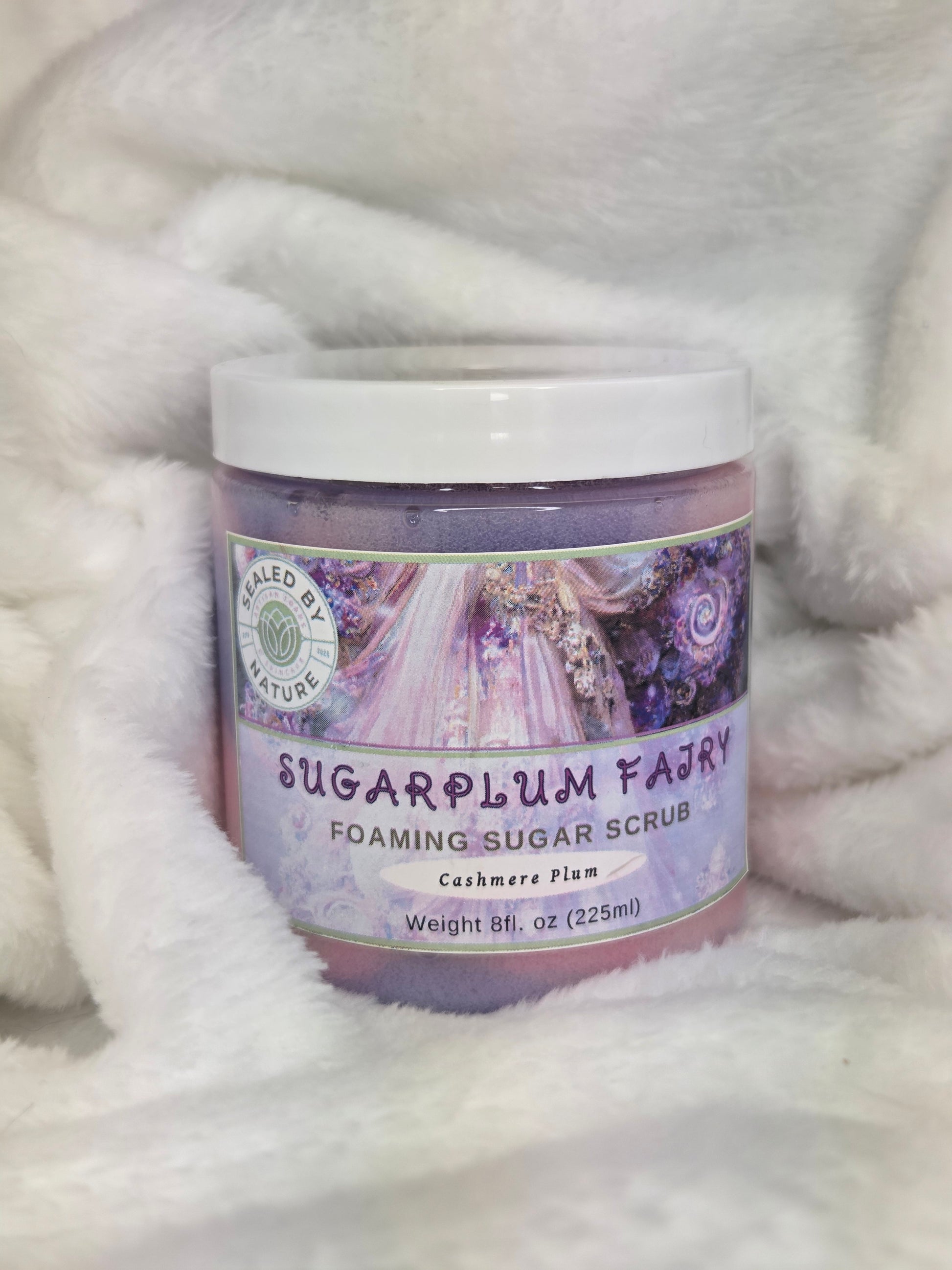 Jar of foaming sugar scrub with decorative label on a fluffy white surface