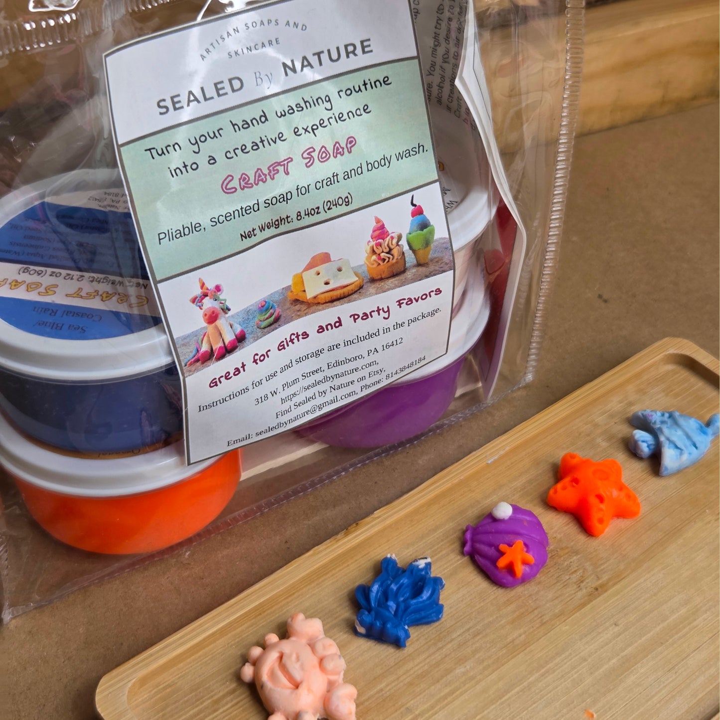 Packaged craft soap with colorful soap shapes on a wooden tray