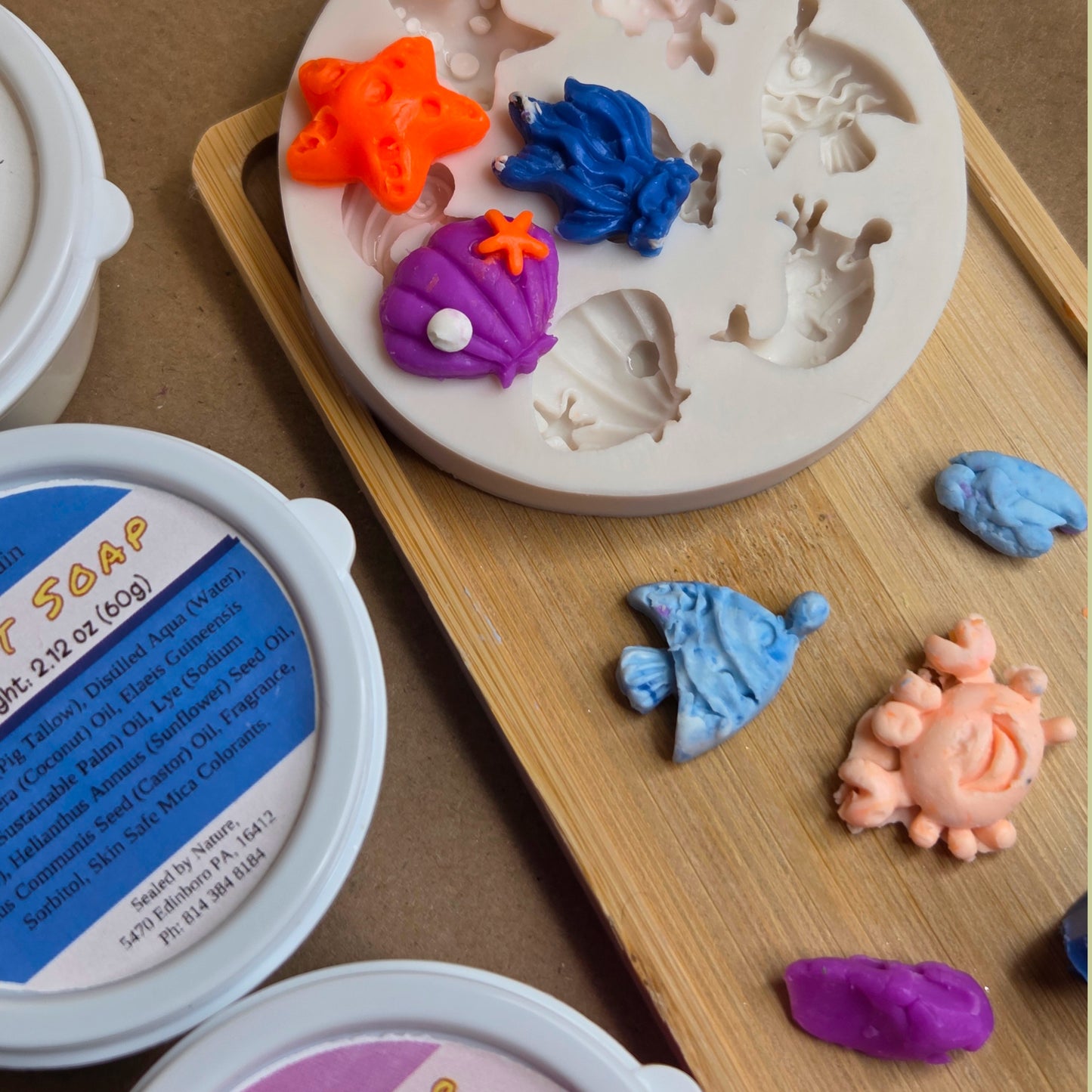 Silicone mold with sea-themed designs on a wooden board, surrounded by colorful clay pieces.