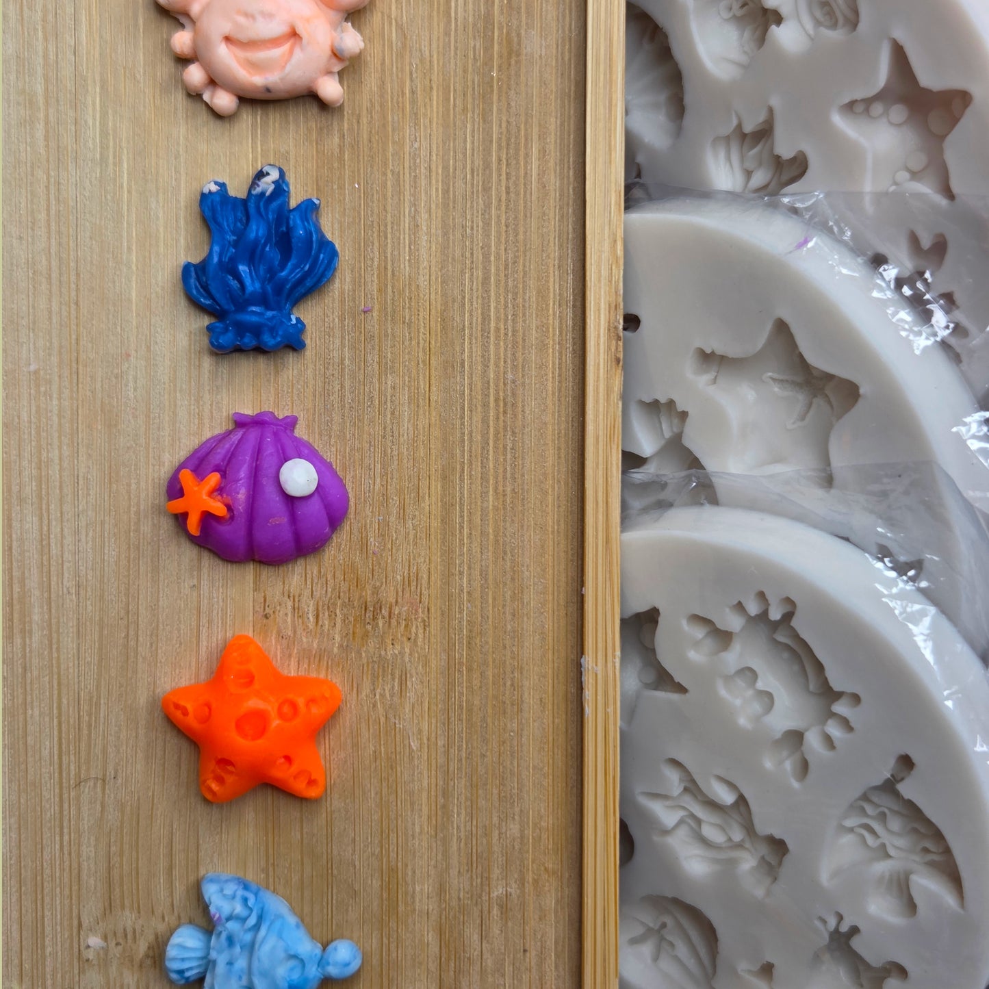 Colorful sea-themed silicone molds on a wooden surface with a close-up of a silicone mold in the background.