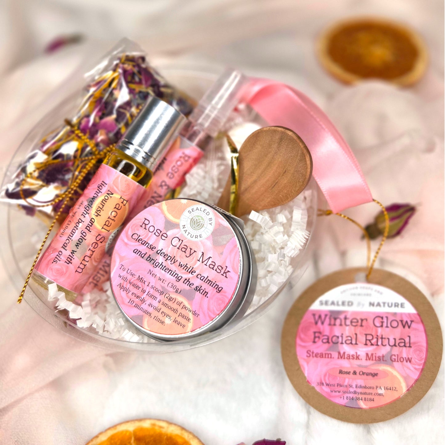 Skincare products with pink packaging on a white surface, including a facial mask and mist bottle.