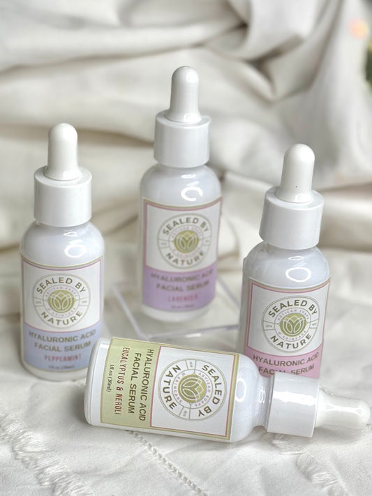 Four skincare serum bottles labeled 'Sealed by Nature' on a textured white surface.