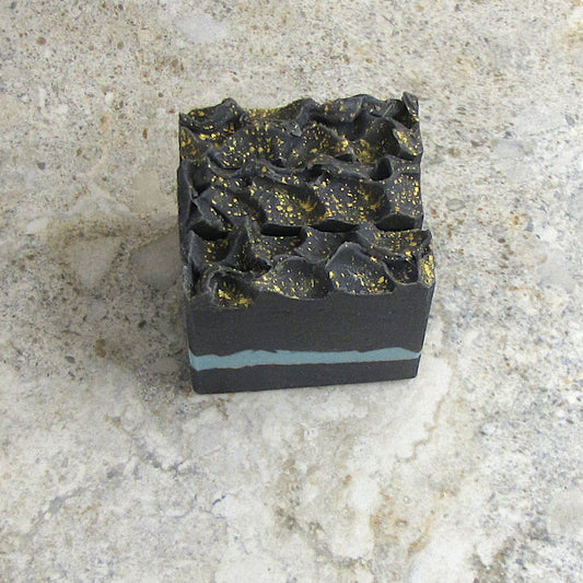 Charcoal and Pumice soap bar on a textured surface.