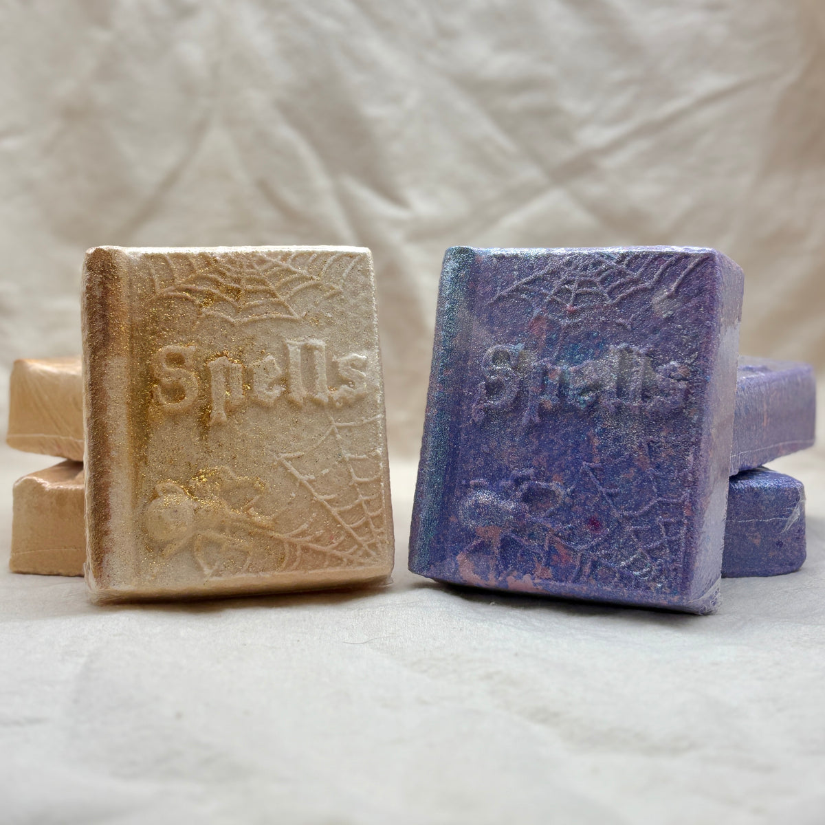 Two Book shaped bath bombs with the word "Spells" on the cover. 