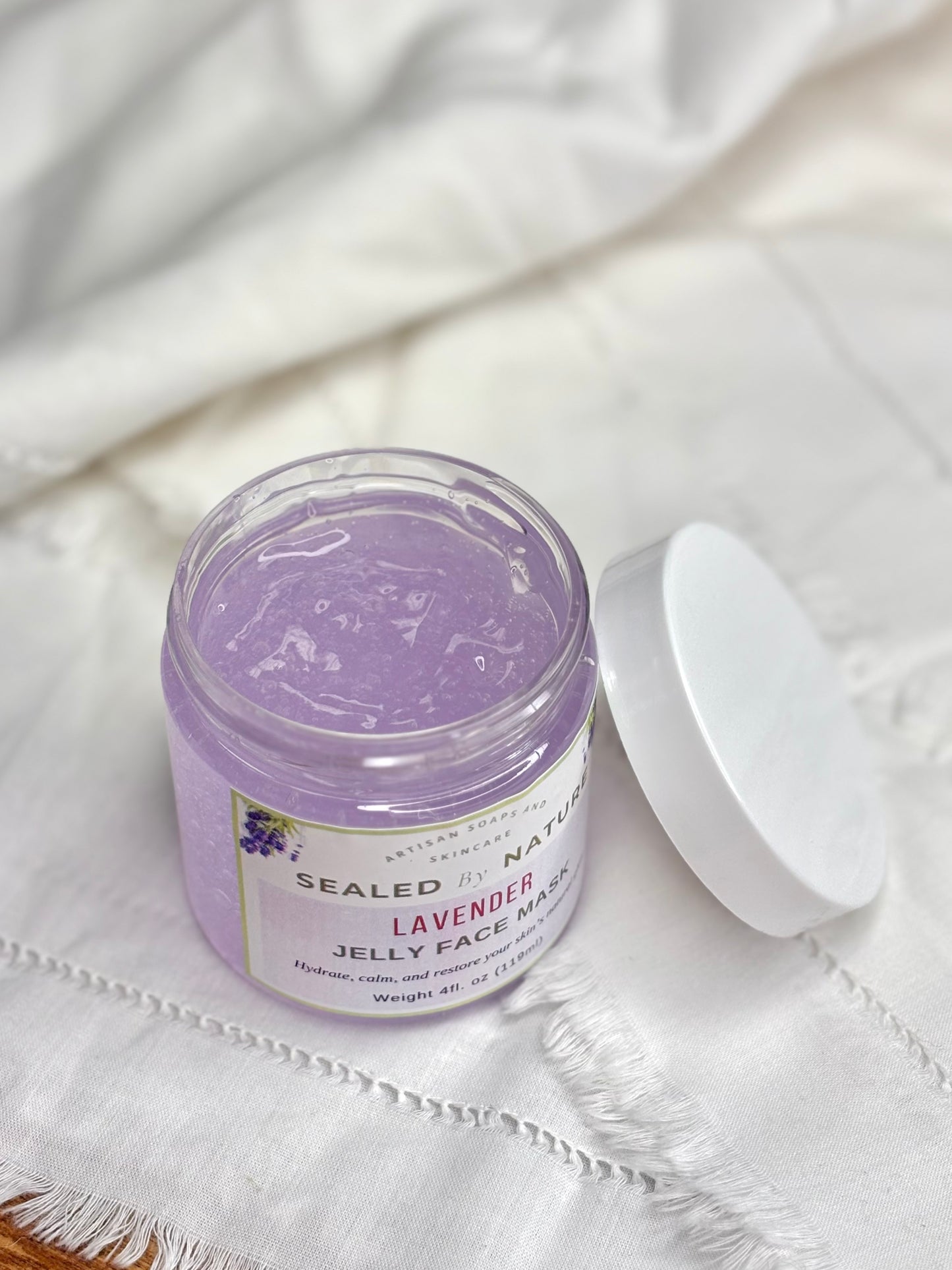 Jar of lavender jelly face mask on a white fabric background