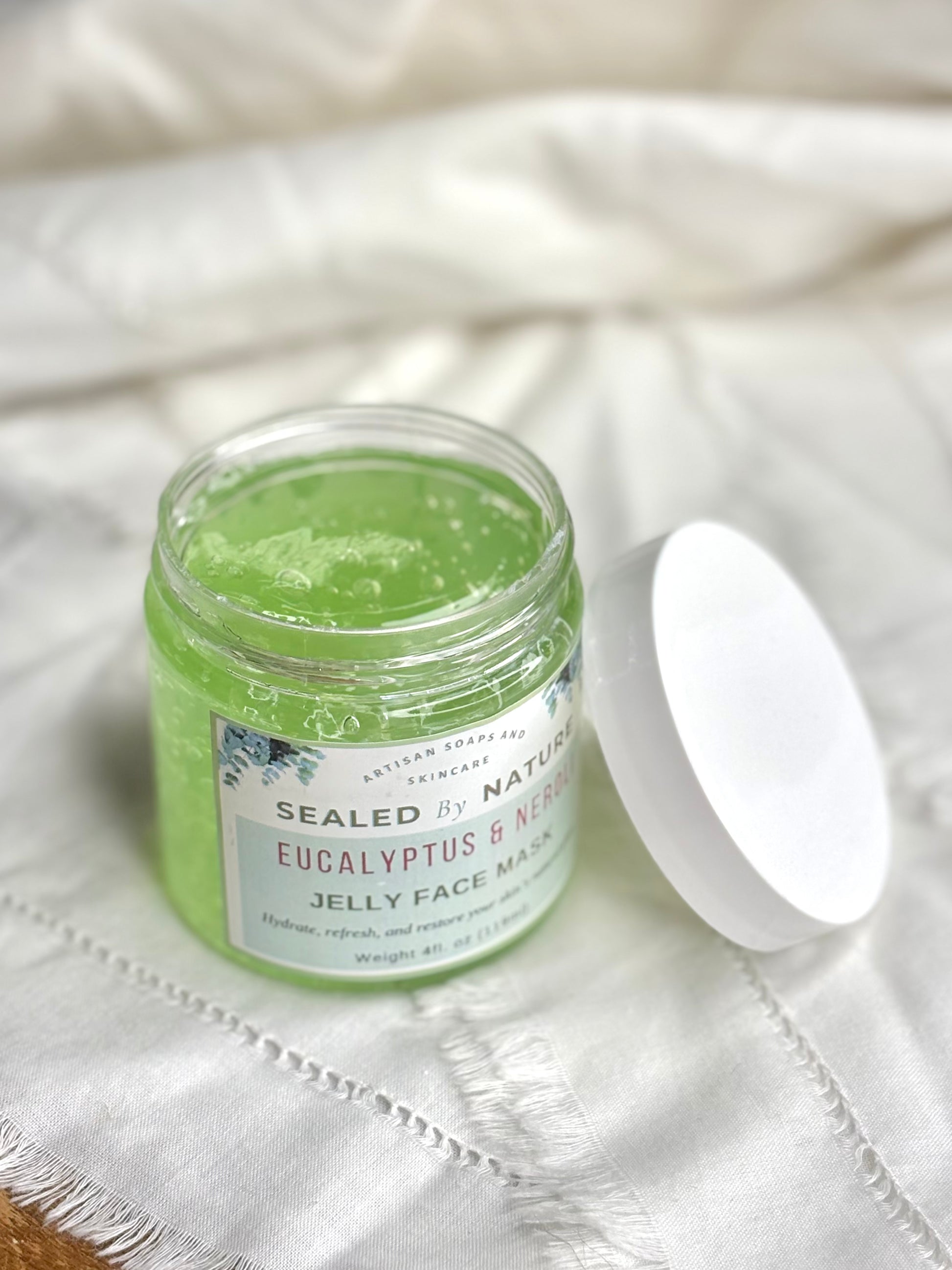 Green jelly face mask in a jar with a white lid on a textured fabric background