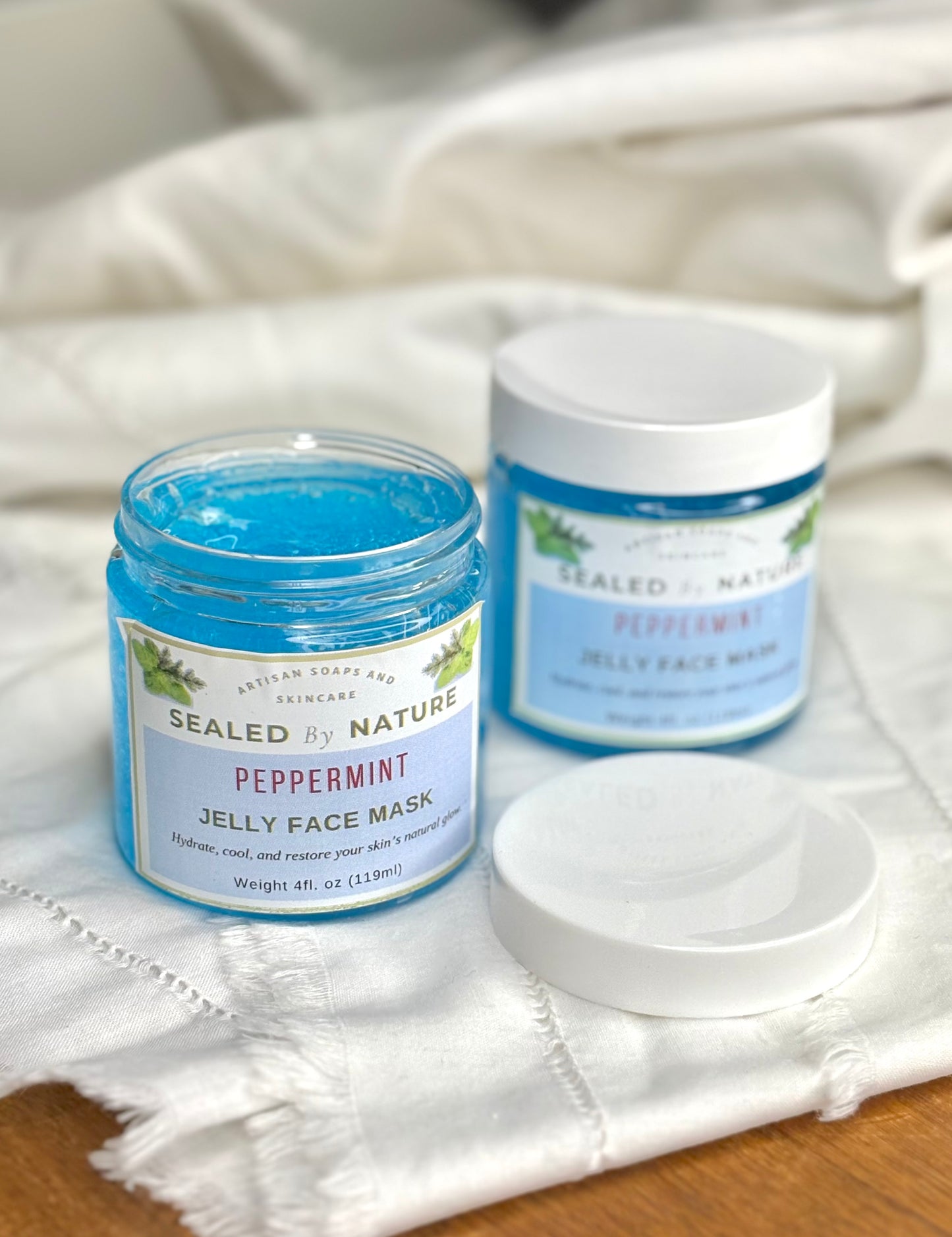 Two jars of Sealed by Nature peppermint jelly face mask on a white cloth.