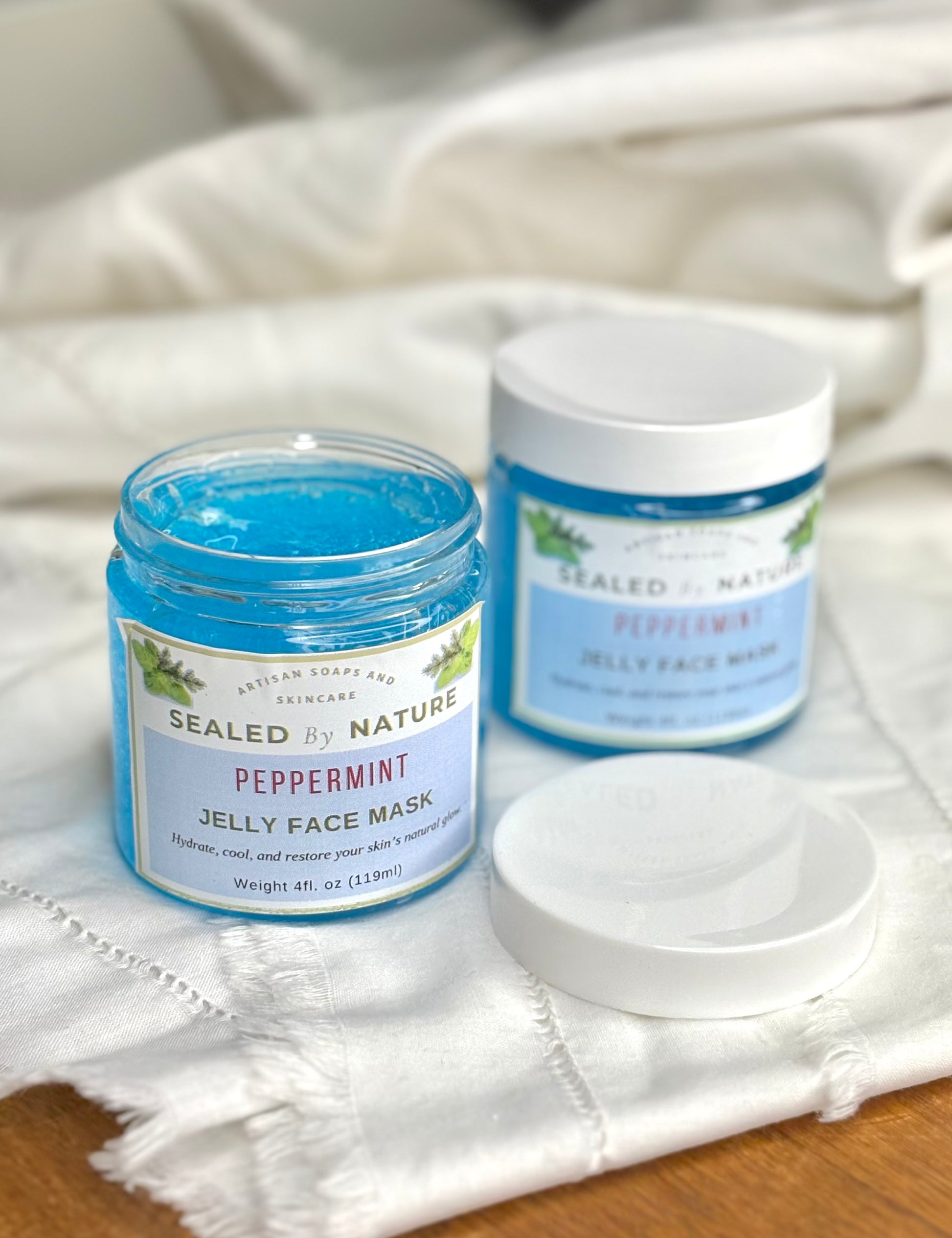 Two jars of Sealed by Nature peppermint jelly face mask on a white cloth.