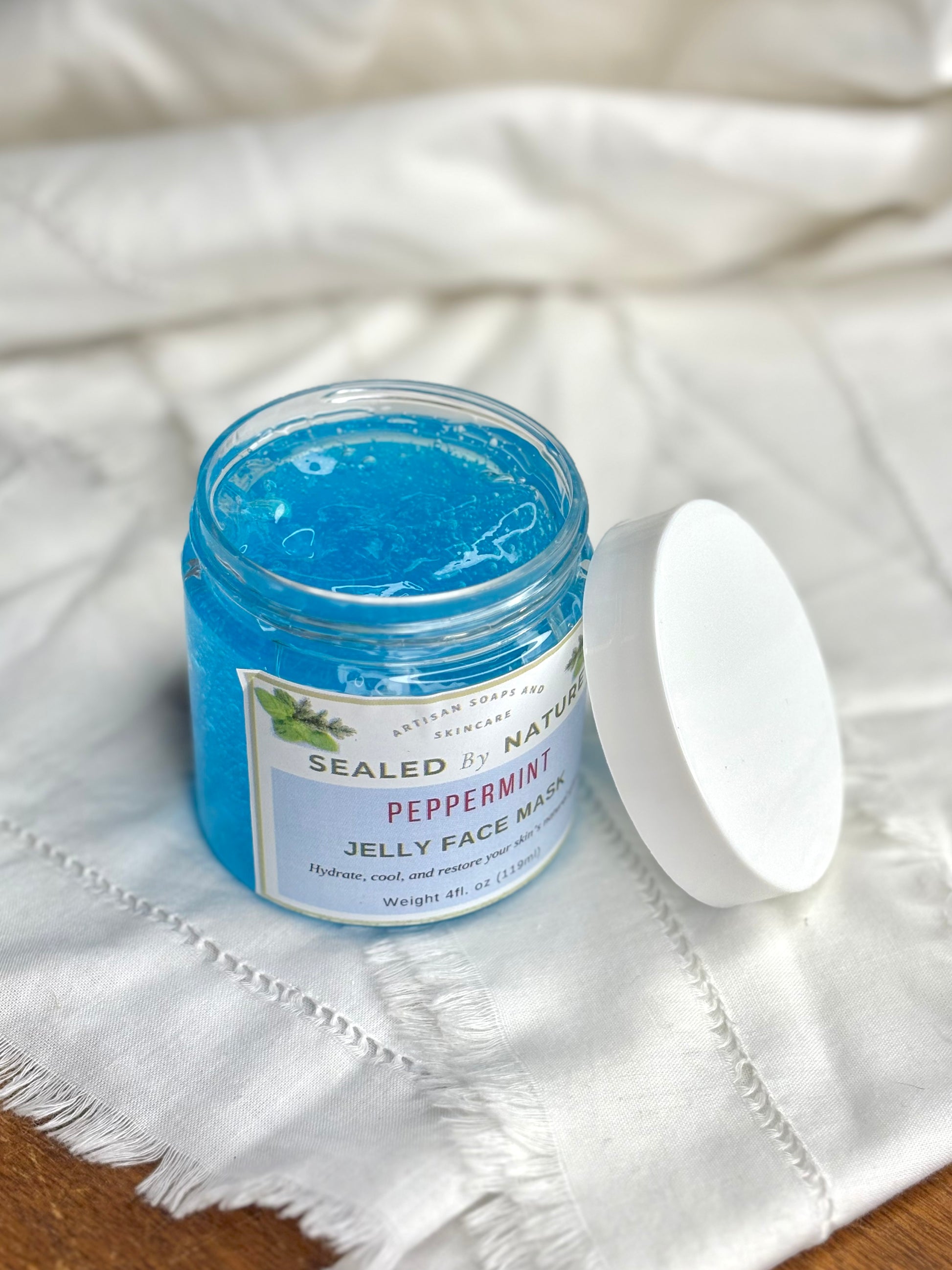 Jar of Sealed by Nature peppermint jelly face mask on a white fabric background