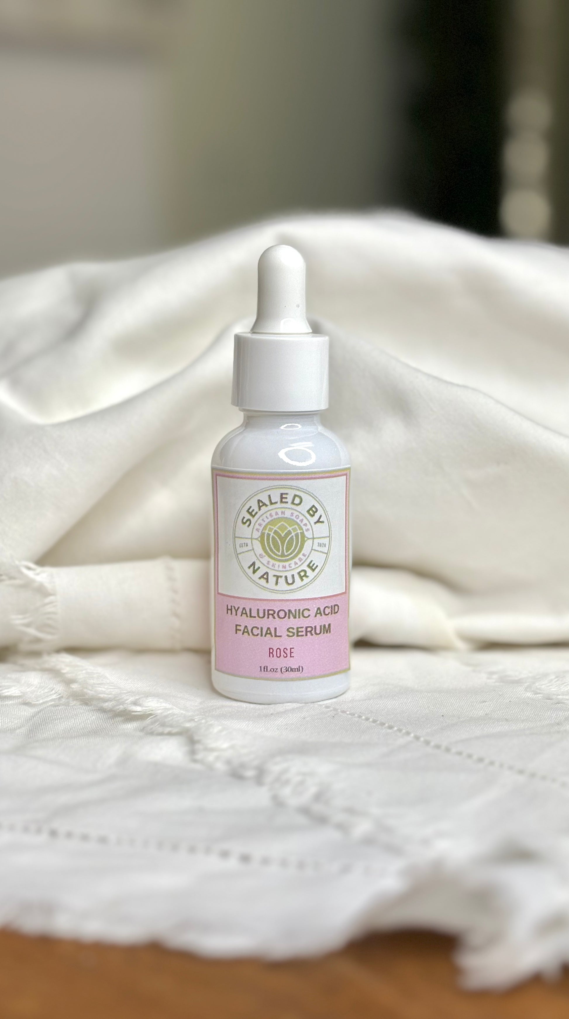 Rose facial serum bottle with dropper on a white fabric background