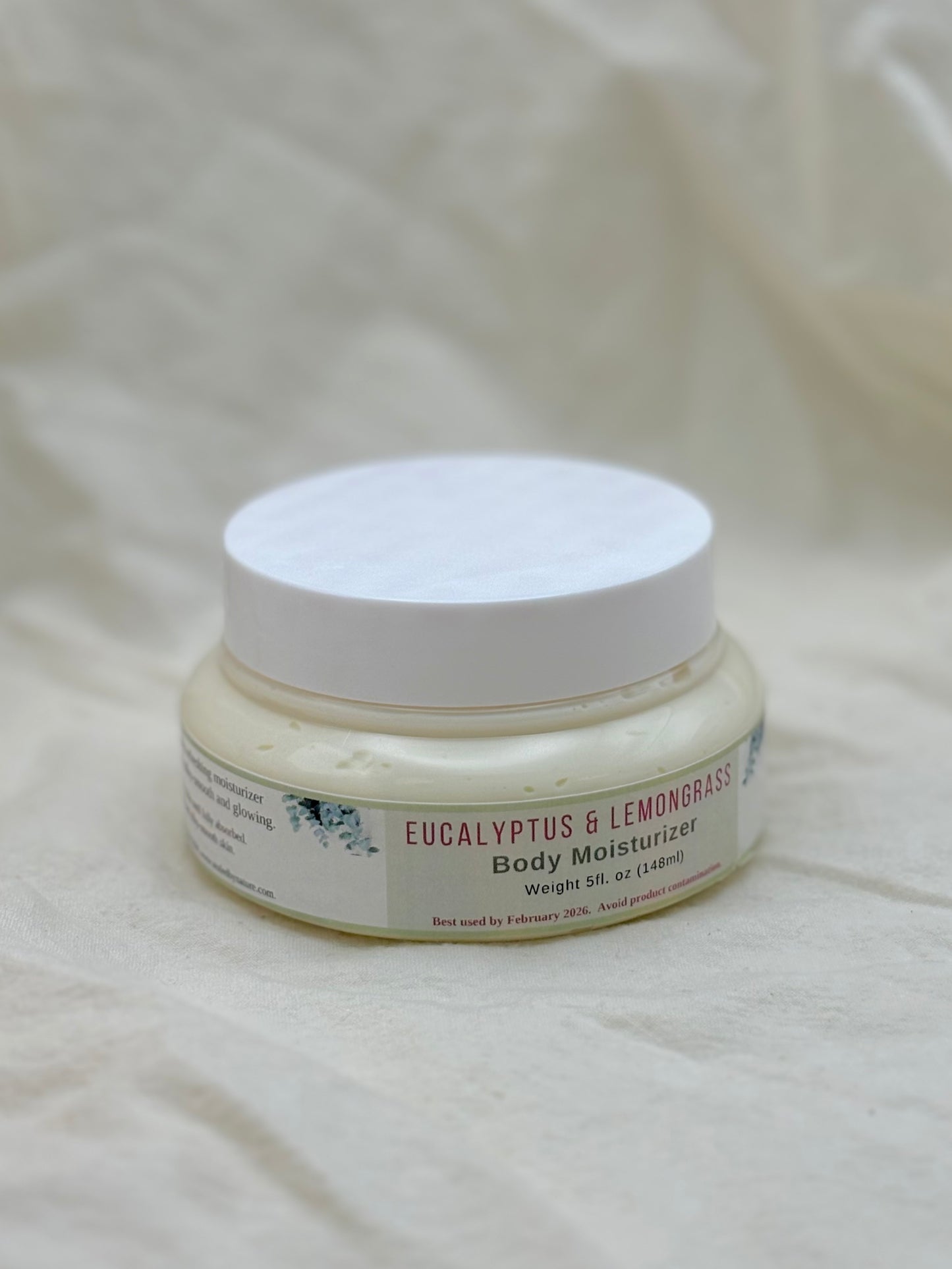 Jar of Eucalyptus & Lemongrass body moisturizer on a textured beige background