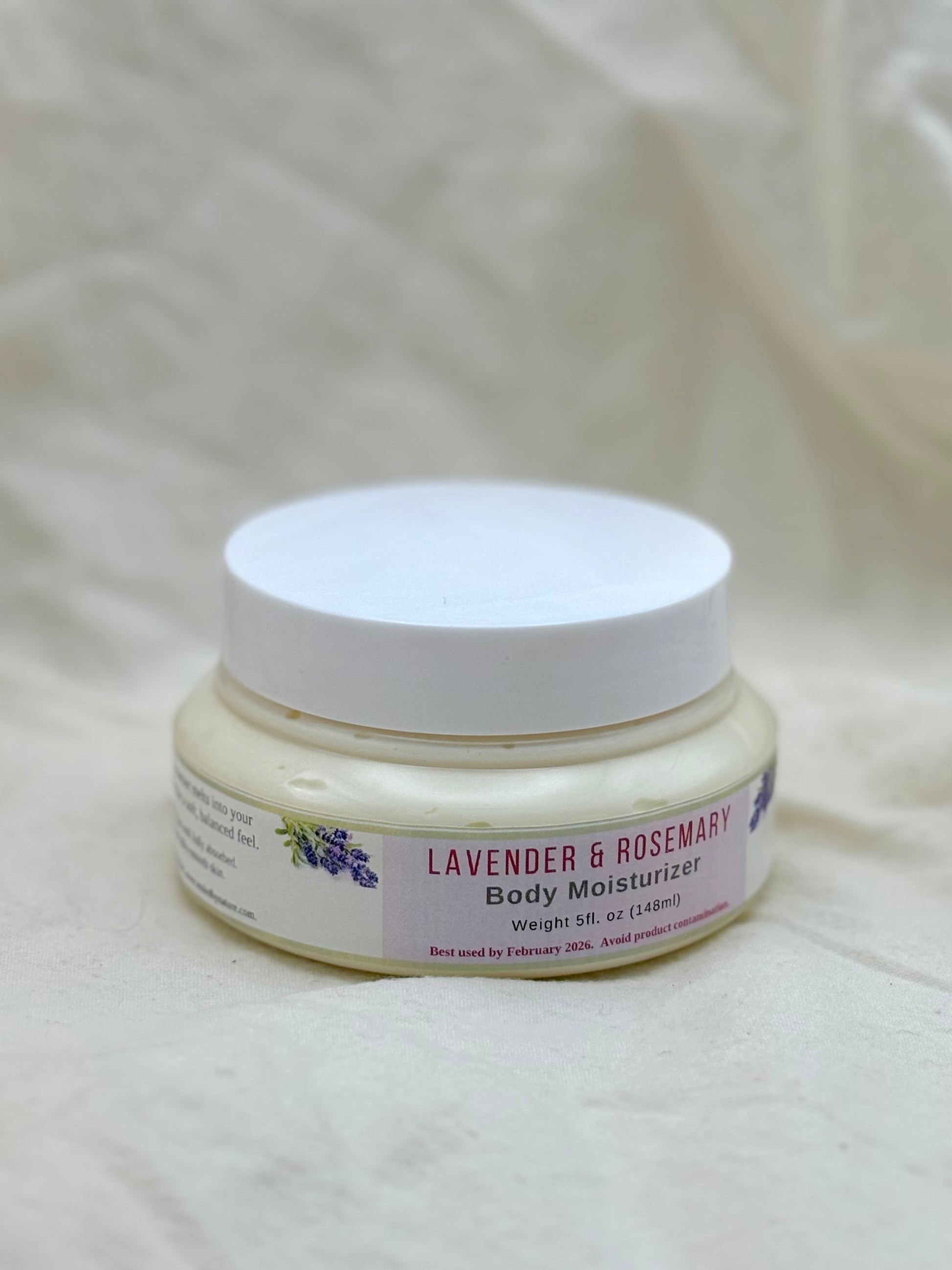 Jar of lavender and rosemary body moisturizer on a textured white background