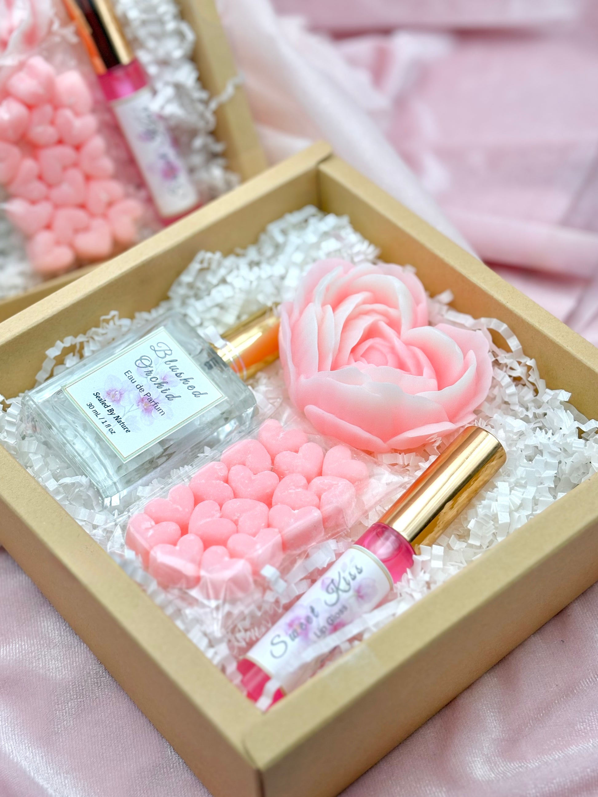 Set of beauty products including a Perfume, lip gloss, and soap flower in a solid heart lotions.