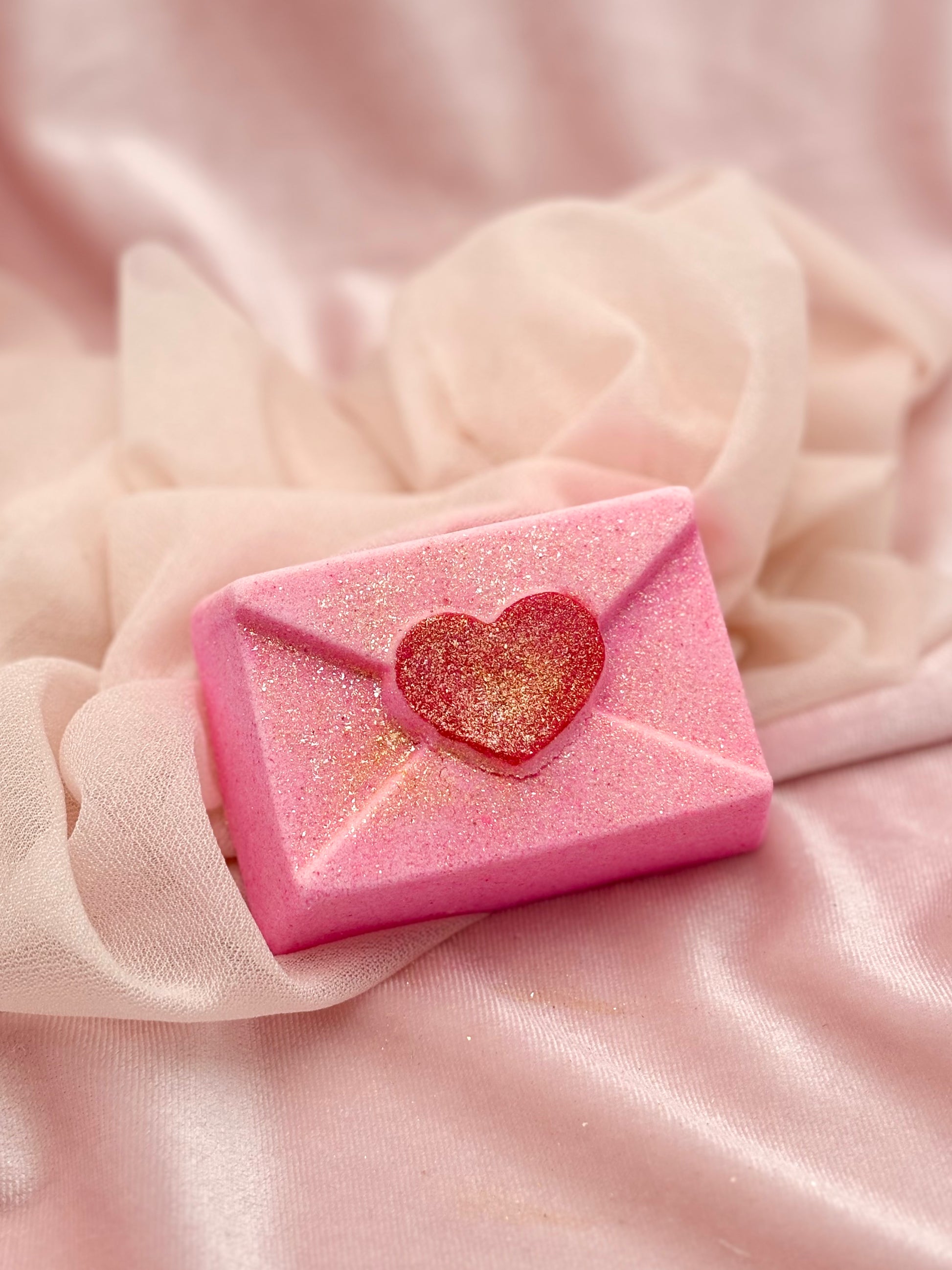 Love Letter Bath bomb in pink color with a heart as a seal on a light pink background