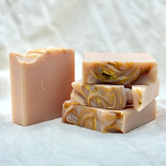 Three bars of soap with gold swirls on a white background