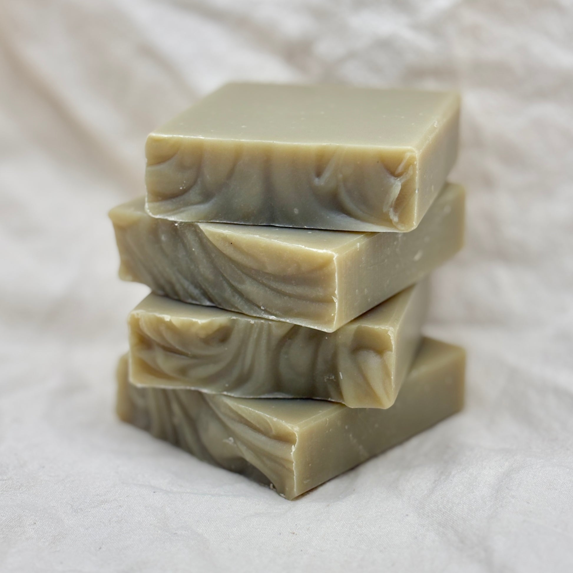 Stack of four bars of soap with a marbled pattern on a white fabric background
