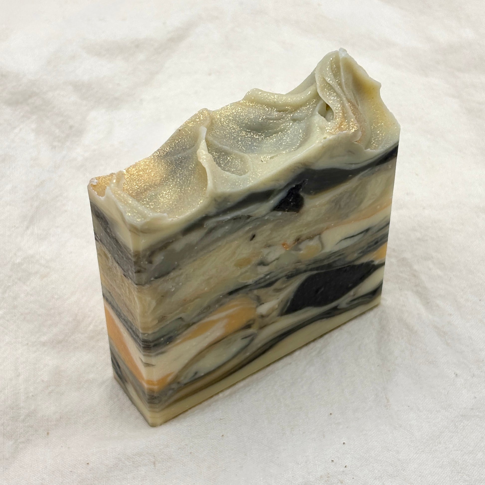 Marbled soap bar with black, white, and beige layers on a white background