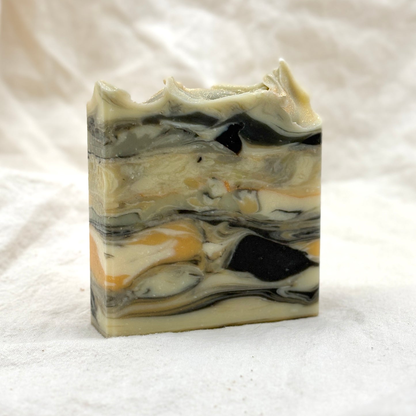 Marbled soap bar with black, white, and beige colors on a white background