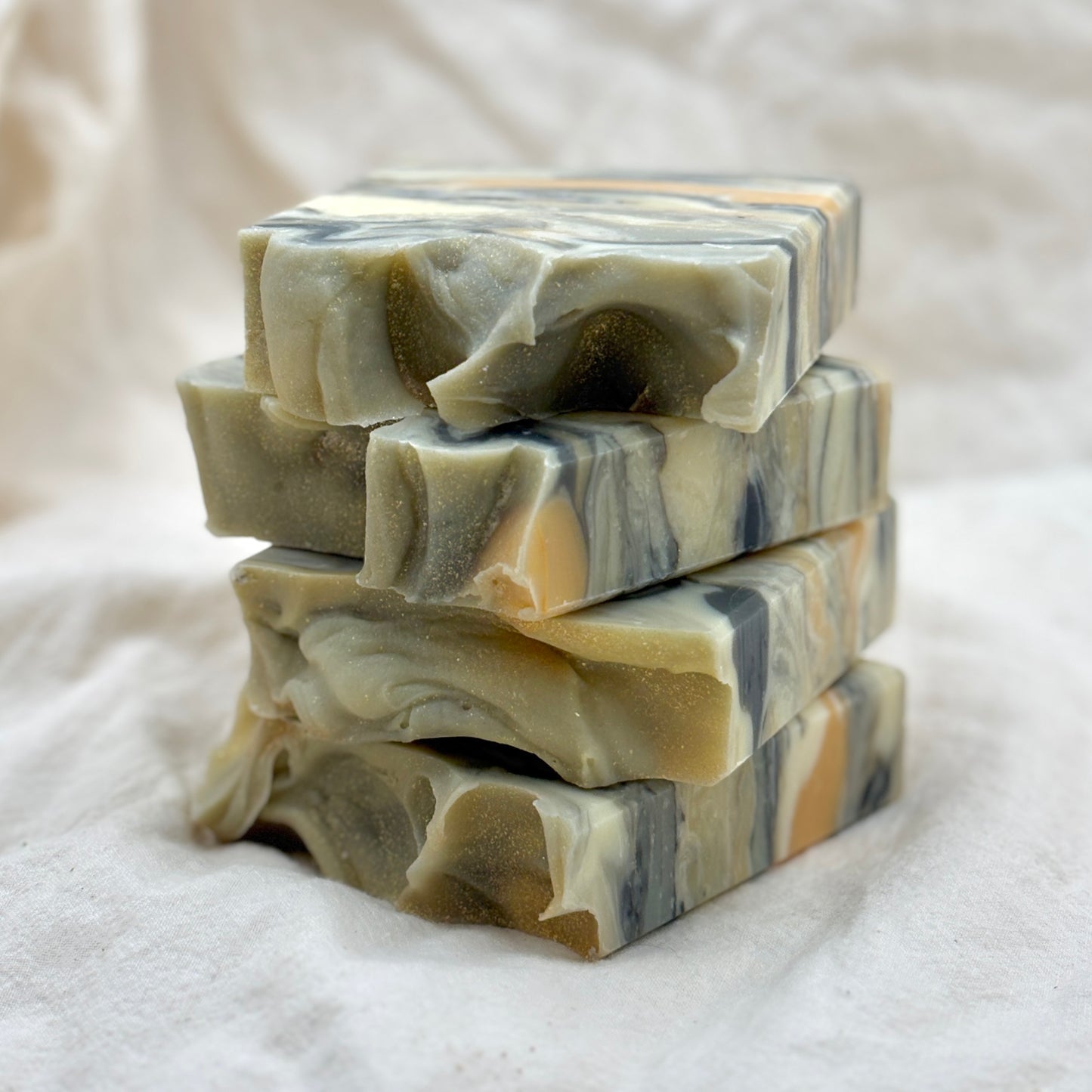 Stack of marbled soap bars on a white fabric background