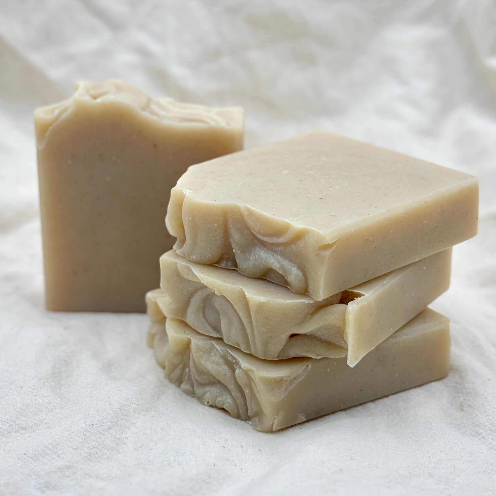 Stack of handmade soap bars on a white fabric background