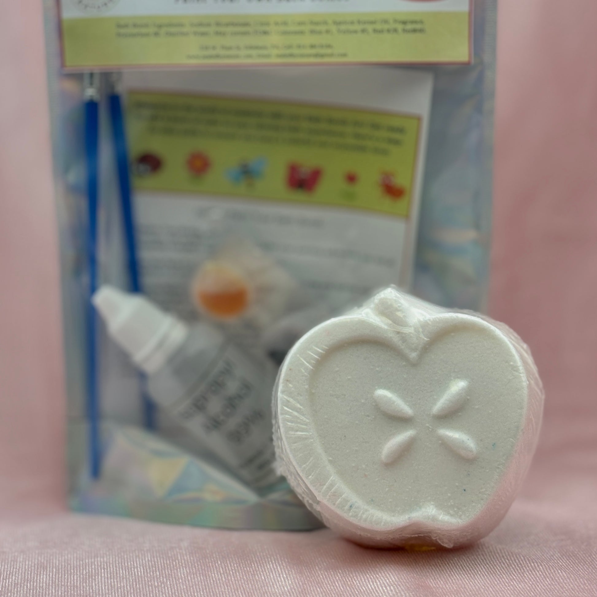 White sliced apple bath bomb for painting with the paint set in the background.