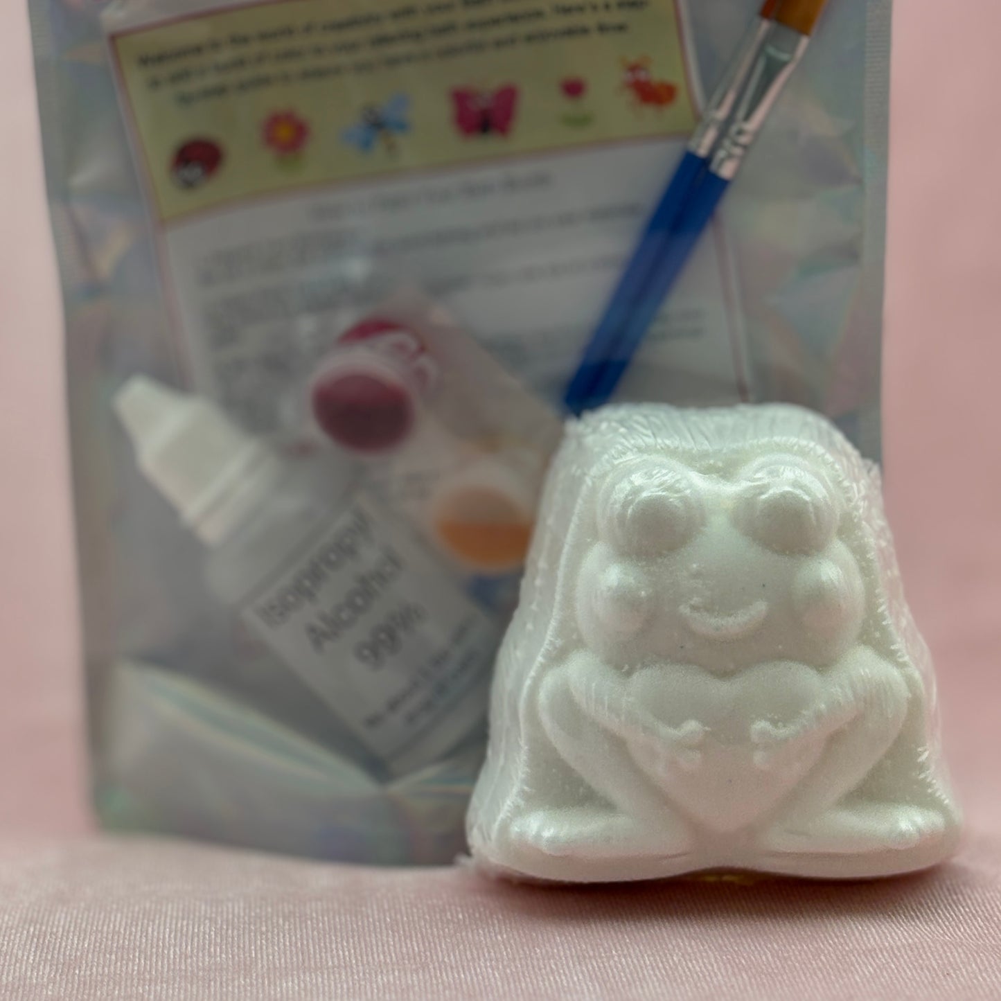 White frog bath bomb intended for painting with a brush and alcohol prep pad in the background.
