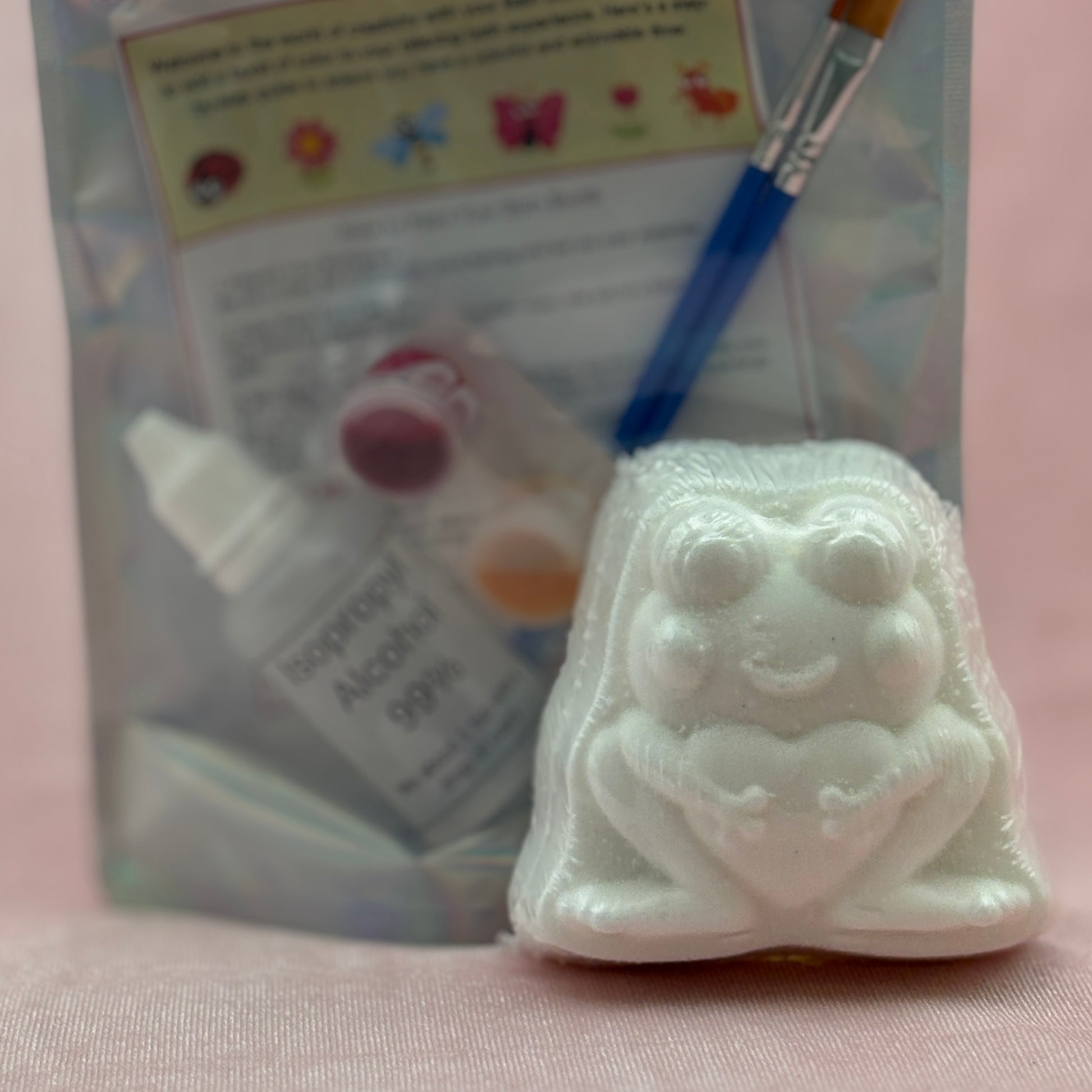 White frog bath bomb intended for painting with a brush and alcohol prep pad in the background.
