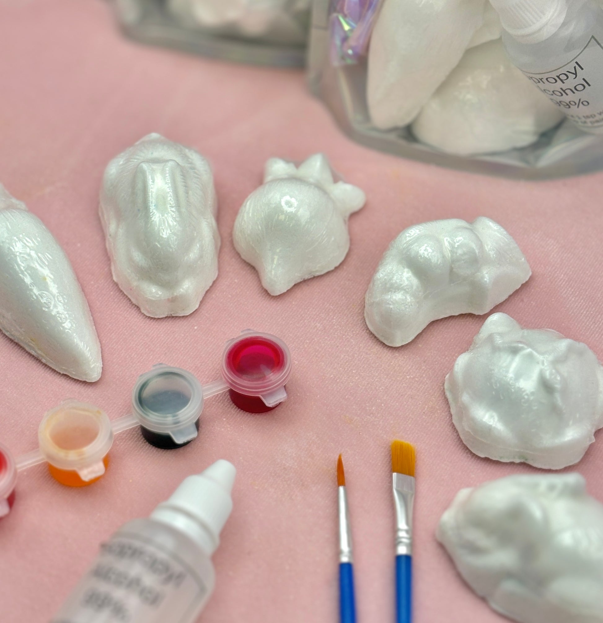 Shell-shaped vegetable bath bombs with paint supplies on a pink surface