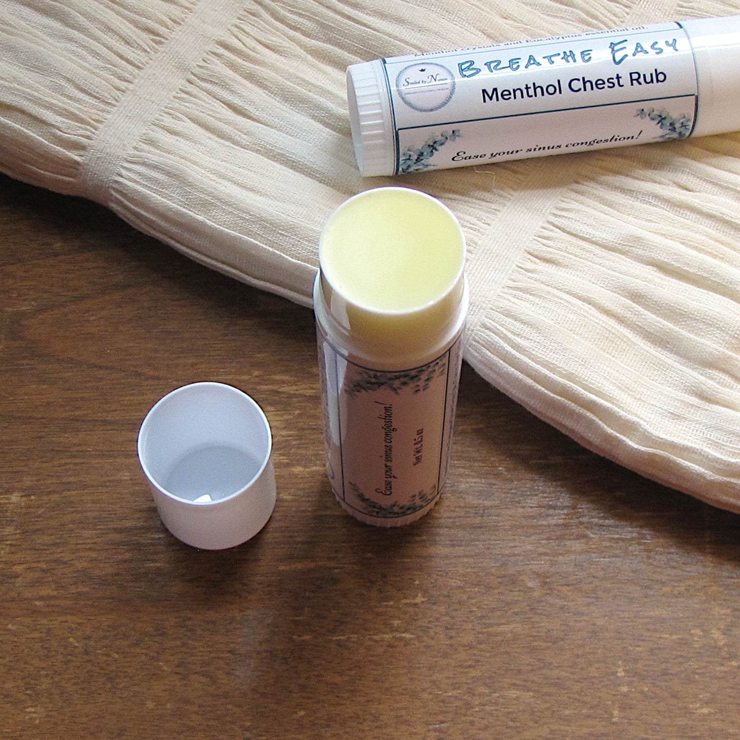 Two bottles of 'Breathe Easy' Menthol Chest Rub on a wooden surface with a white cloth in the background.