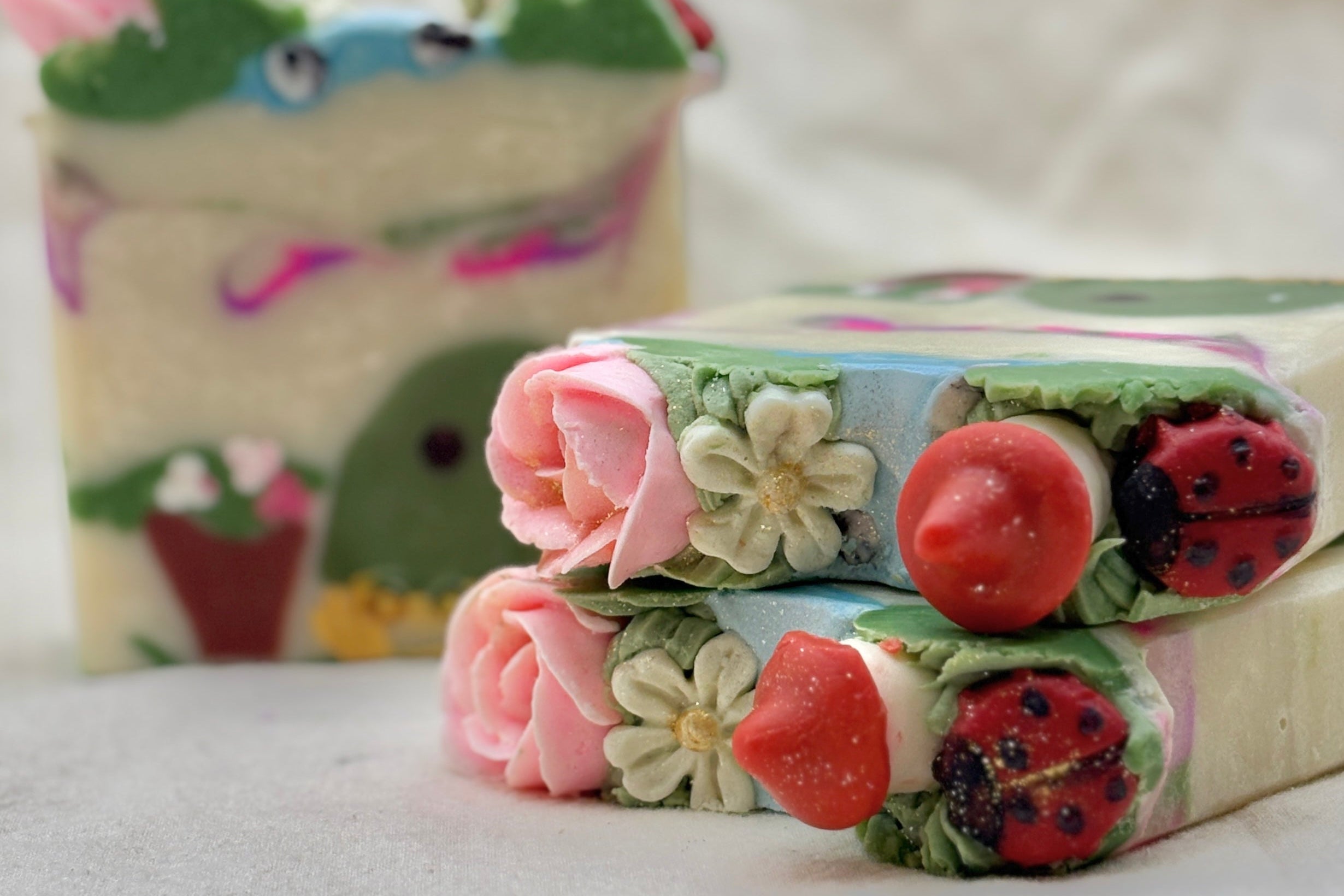 Decorative soap bars with floral and ladybug designs on a white background