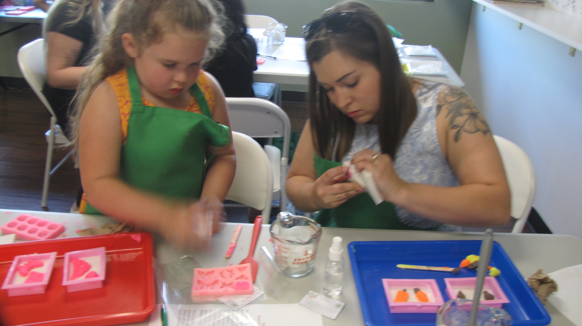 A woman and a child working with soap dough and meltable soap to create bar soaps.
