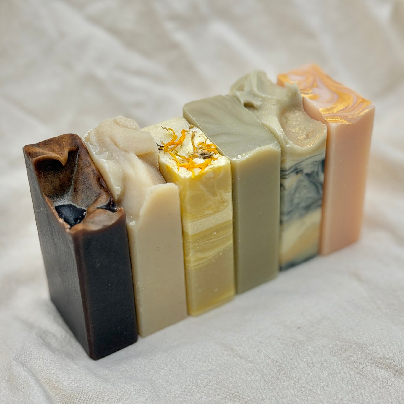 6 different bars of half size soaps on a white background.